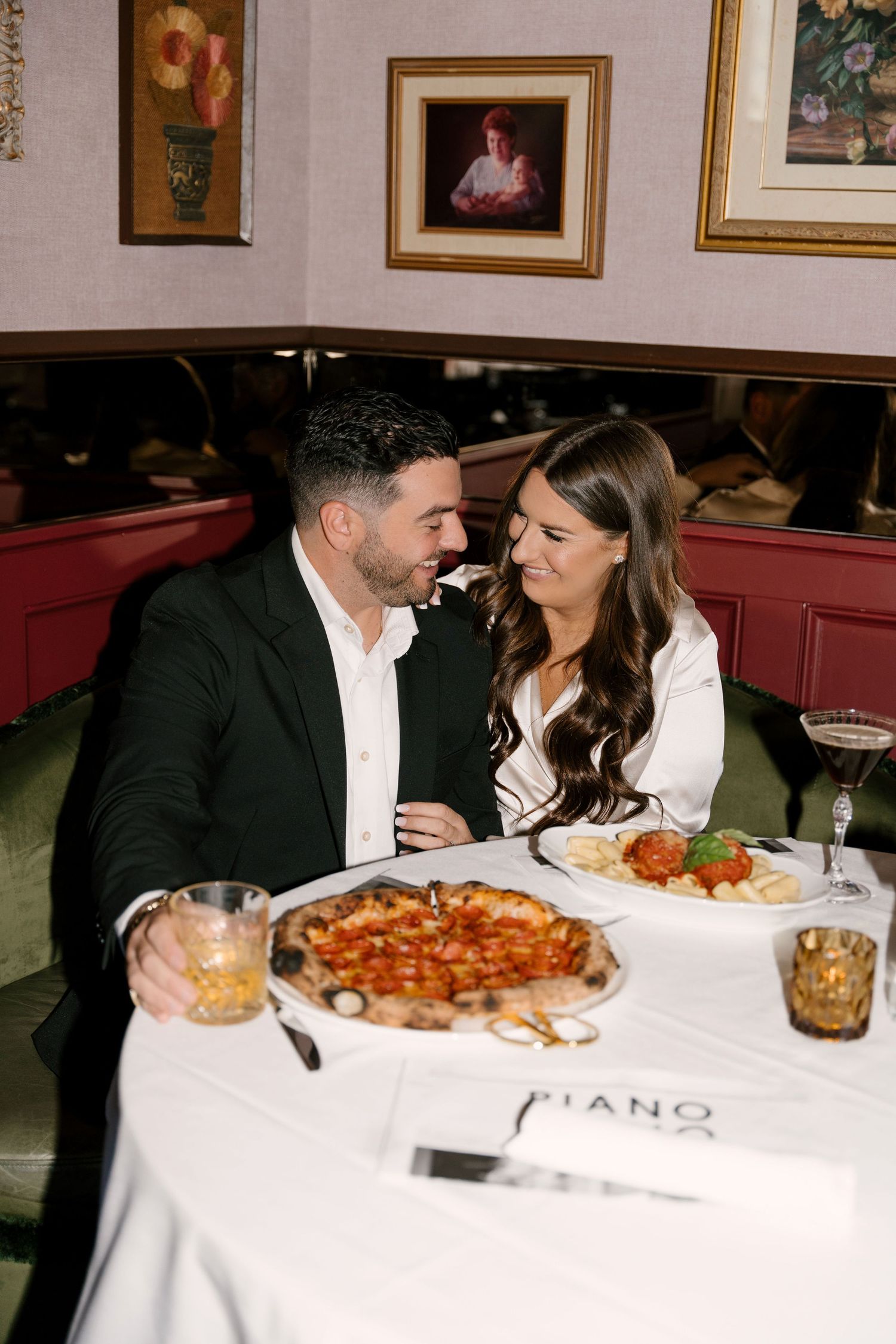 Couple smiling at each other over pizza and pasta at Piano Piano restaurant on a romantic date.
