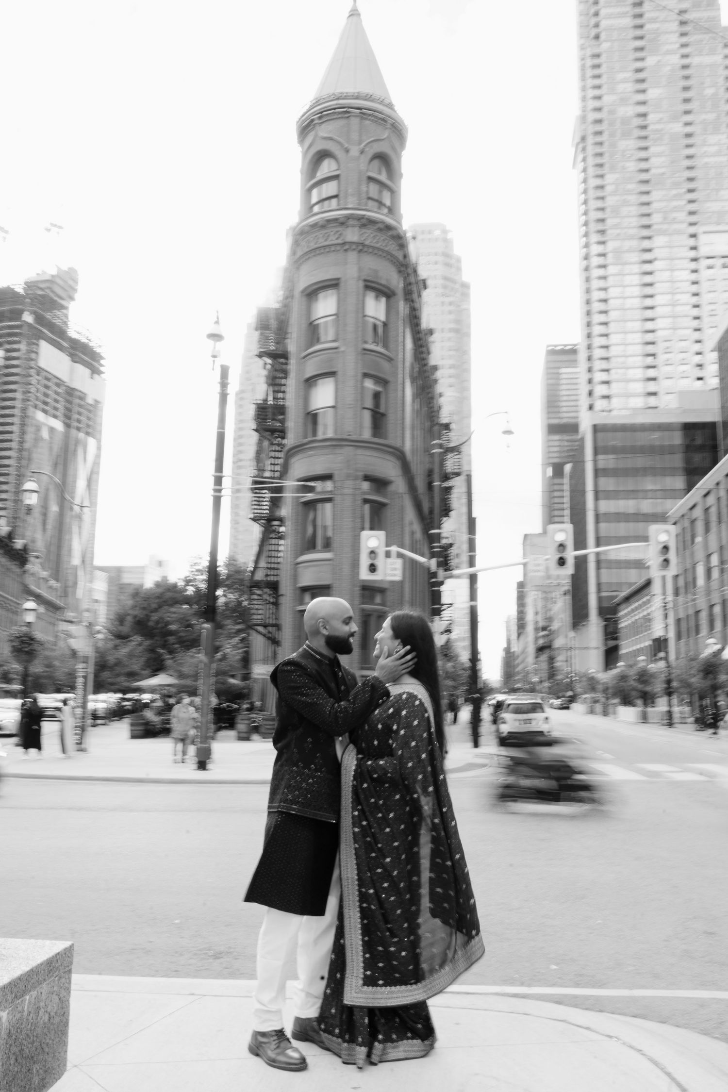 Indian couple in traditional attire share a romantic moment near Toronto Gooderham Building.