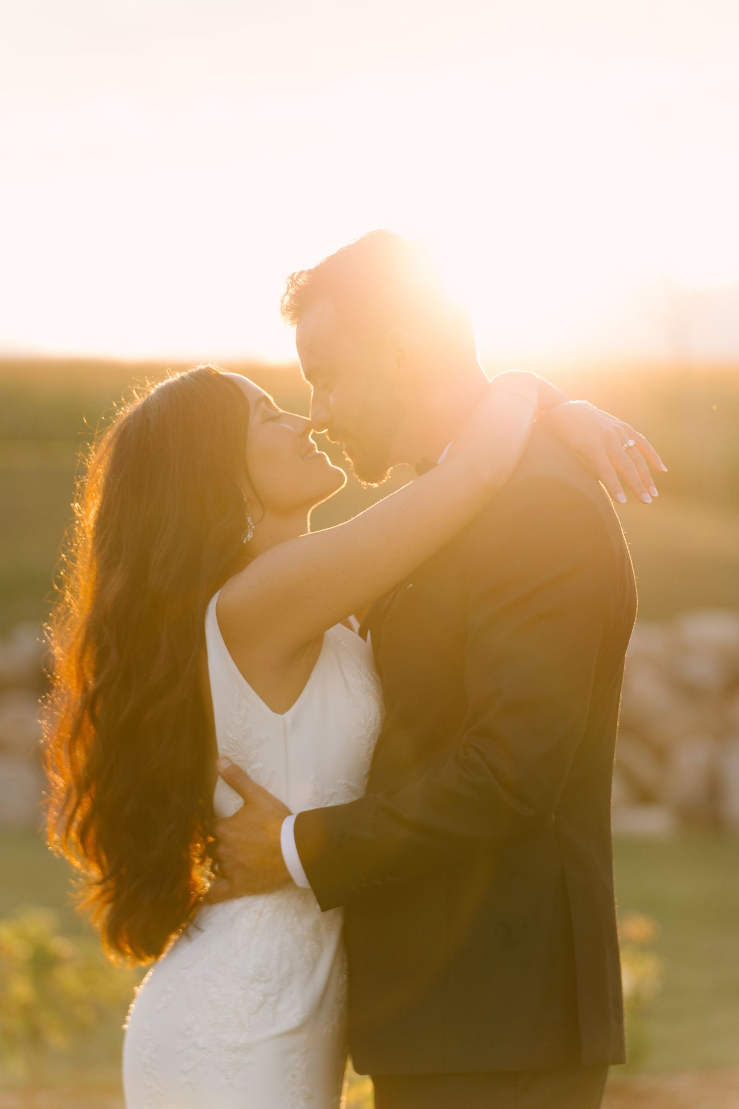 Couple sharing an intimate embrace bathed in warm golden sunset light on their wedding day.