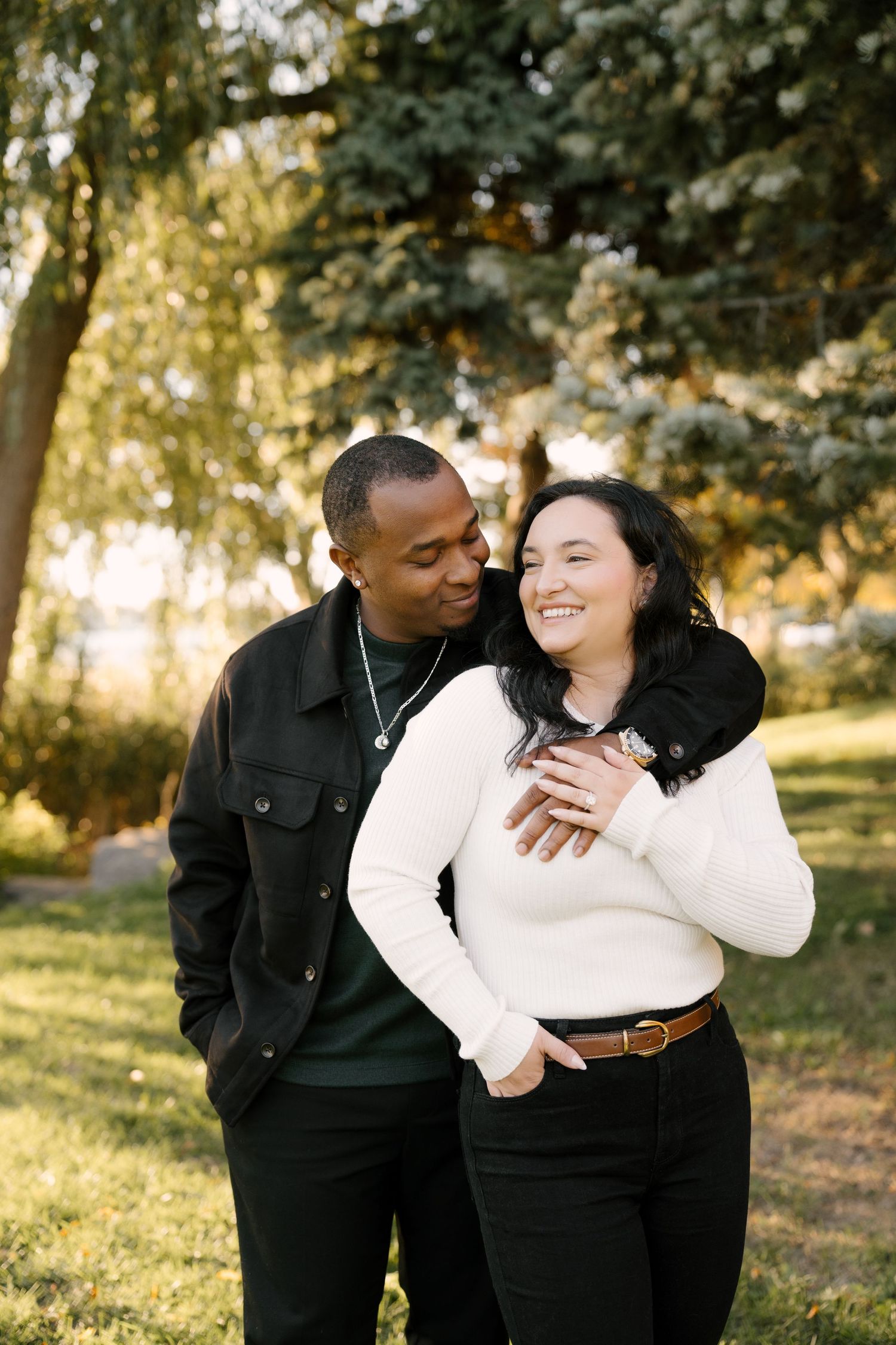 Happy interracial couple embracing and smiling together in a sunny autumn park setting.