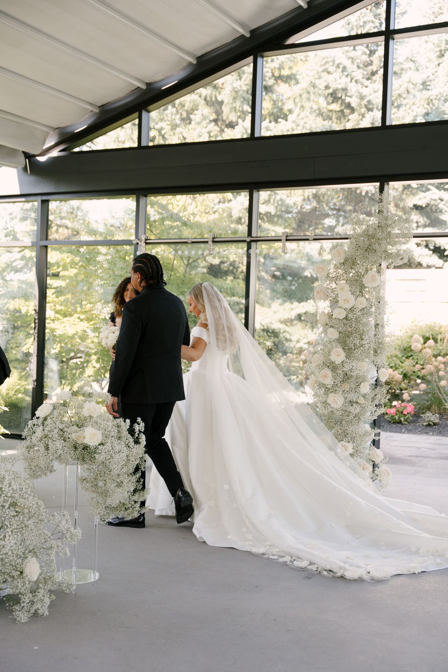 Bride and groom sharing first kiss at floral altar in glass chapel venue at Whistle Bear wedding venue.