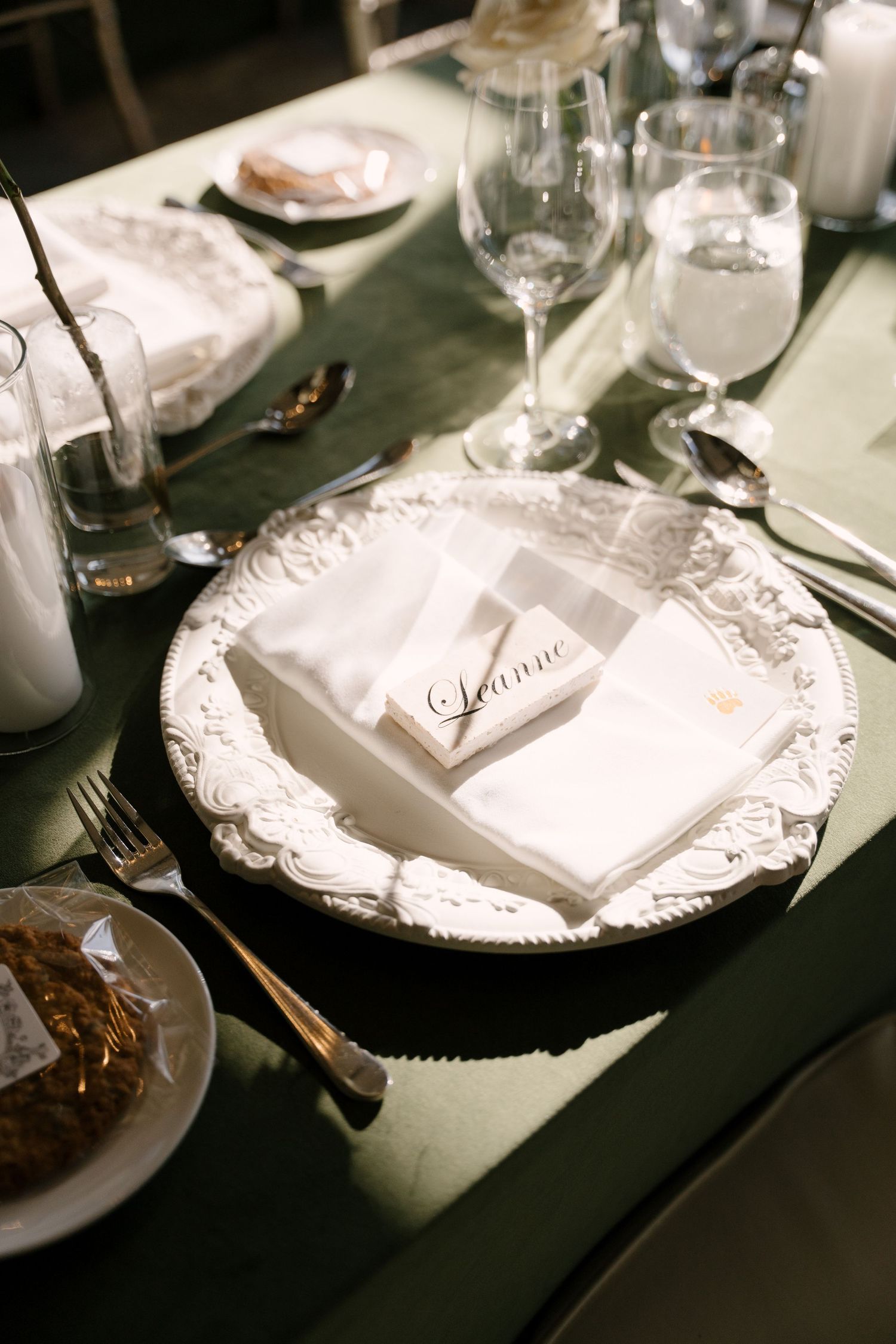 Elegant wedding place setting with ornate white charger plate and personalized name card.