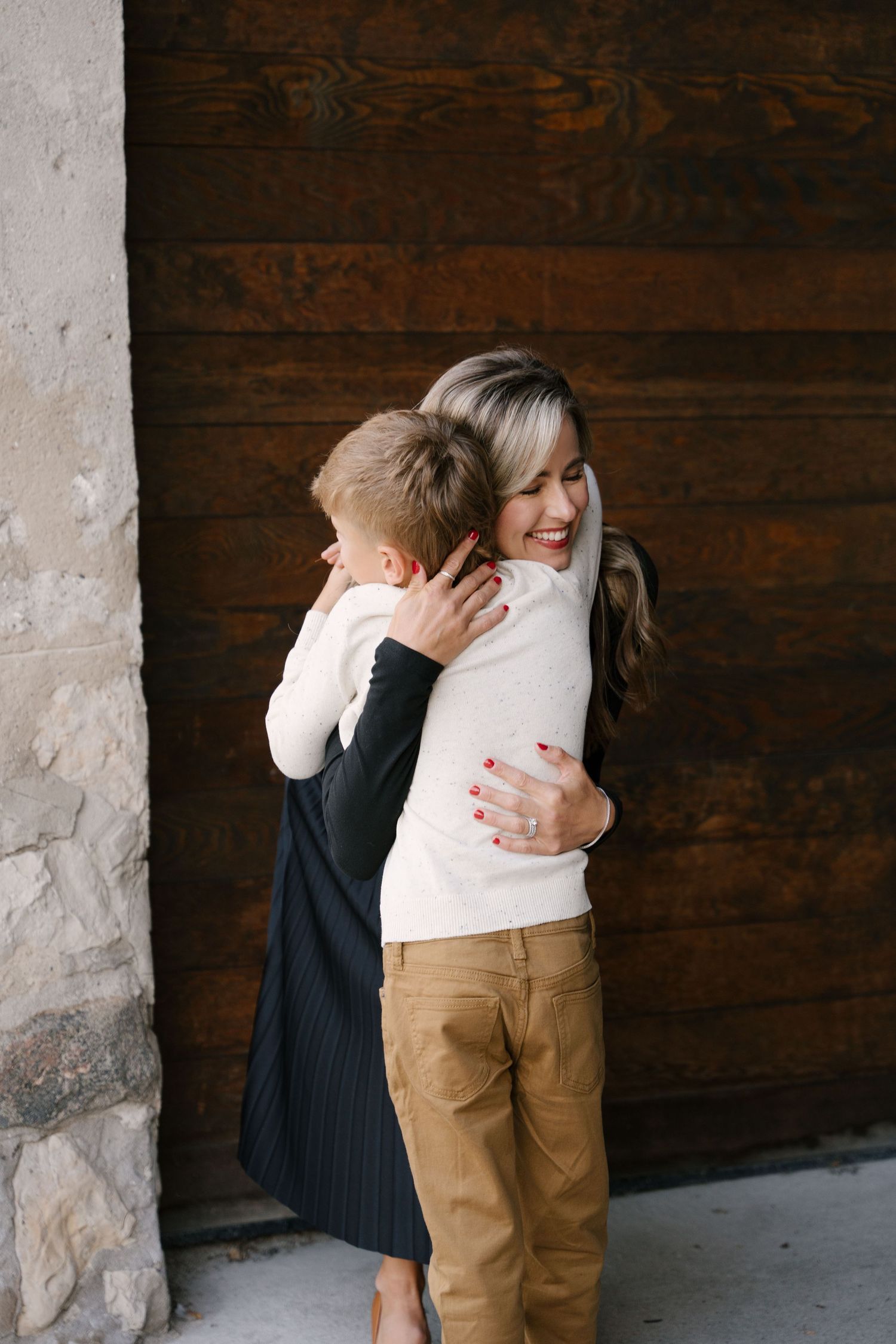 Joyful mother and son sharing a warm hug against a rustic wooden door.