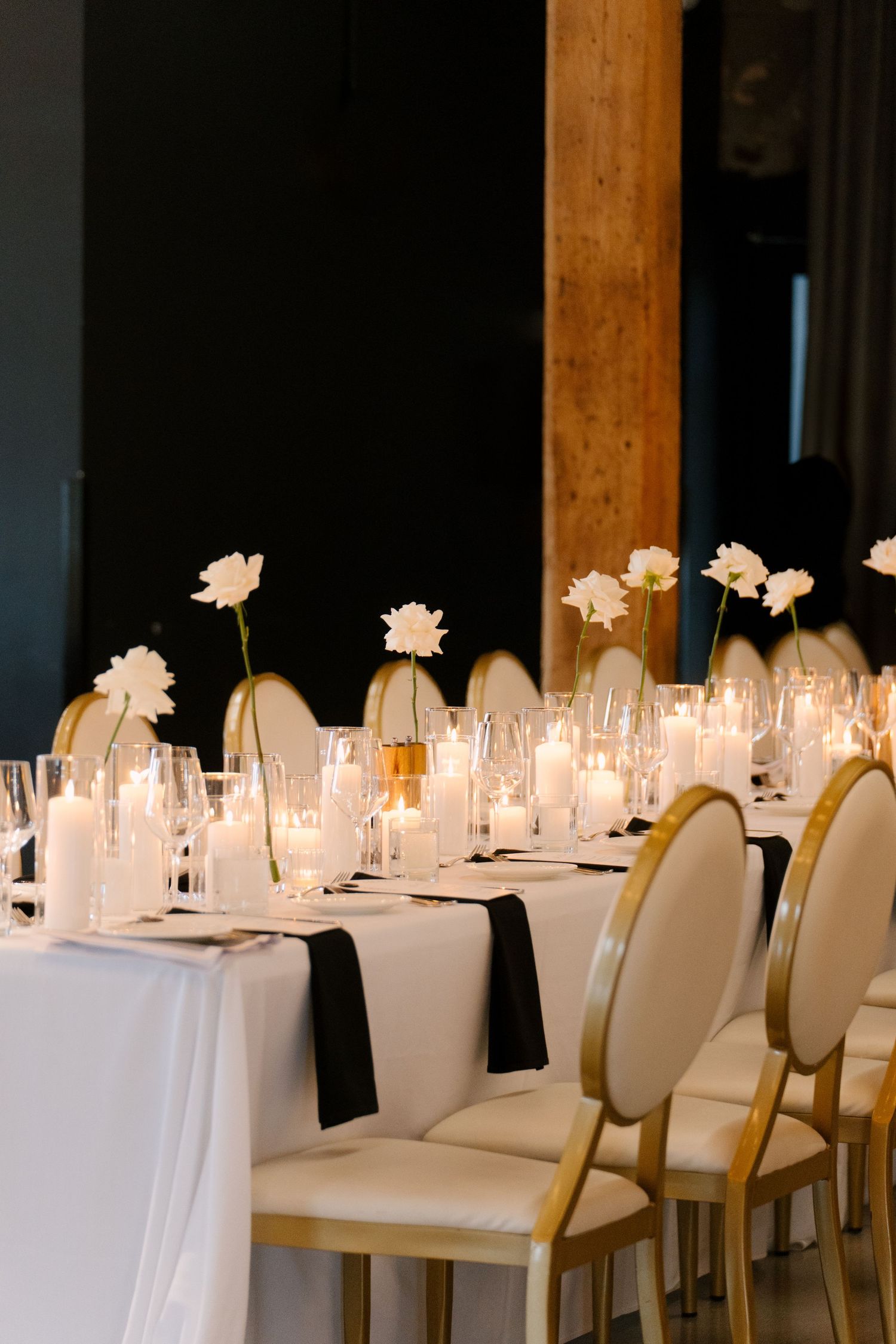 Elegant wedding reception table with white florals, candles, black napkins, and gold chairs at Tapestry Hall wedding venue.