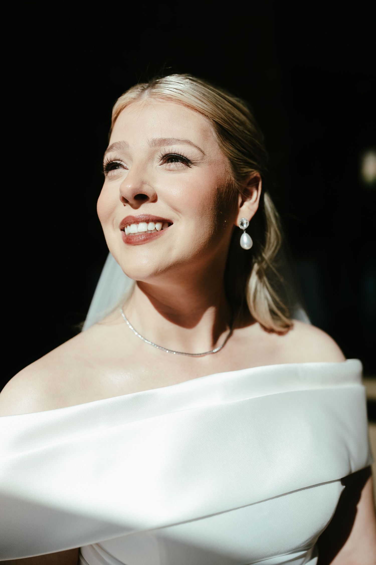 Elegant bridal portrait featuring off-shoulder white wedding dress detail.