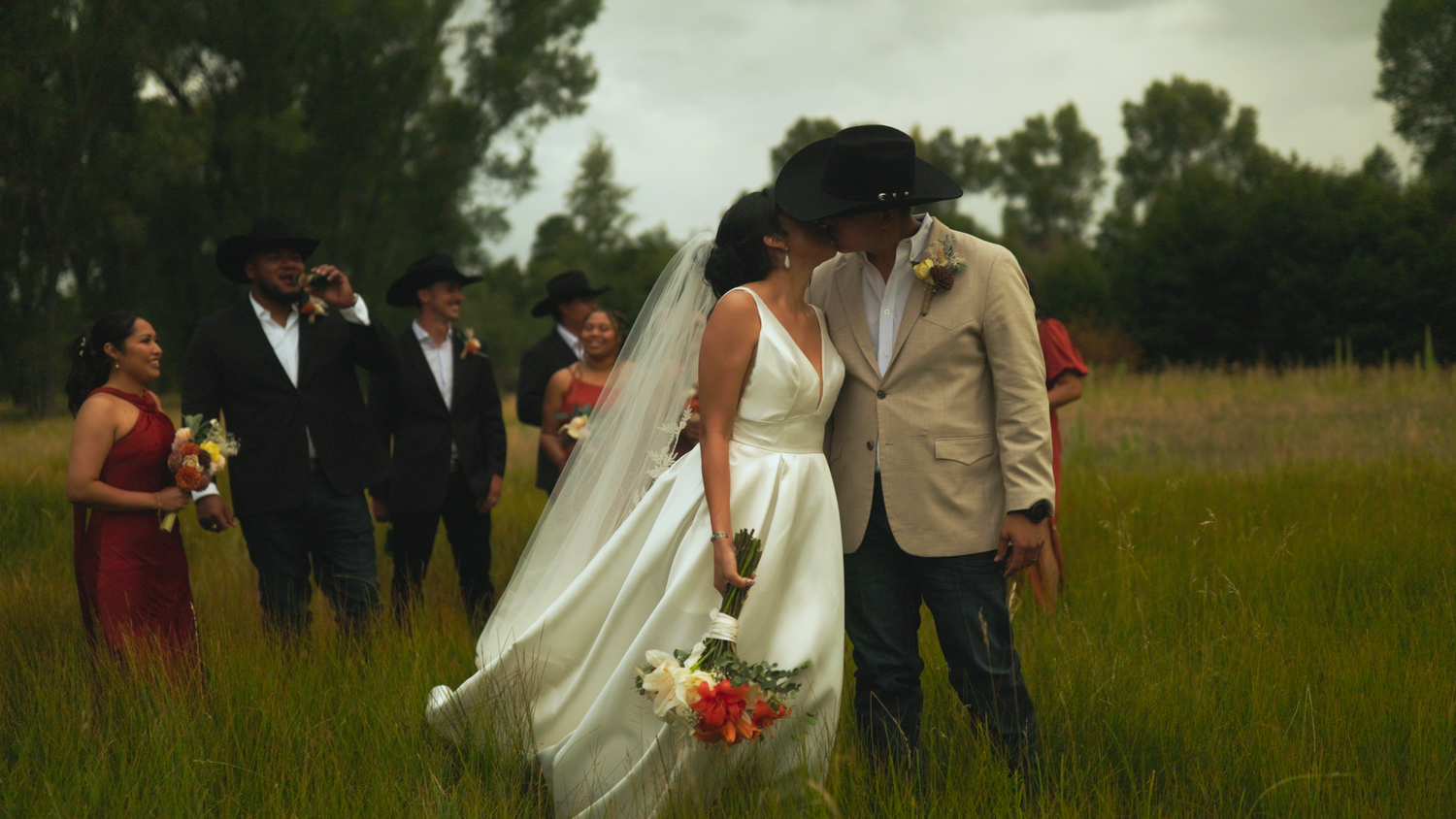 Wedding party walking through a scenic field with trees in the background.
