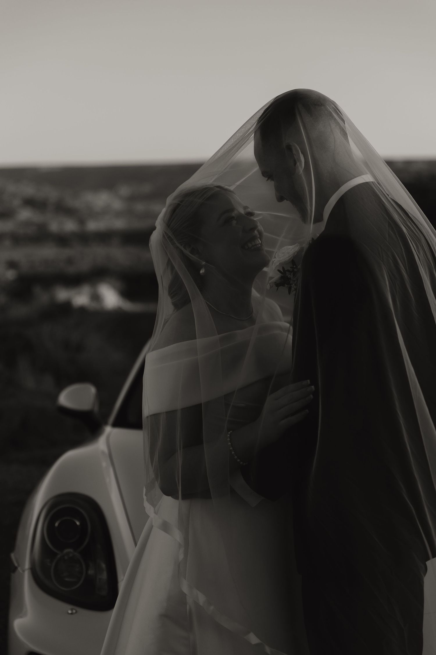 Ethereal black and white wedding portraits with flowing veil creating dramatic composition.