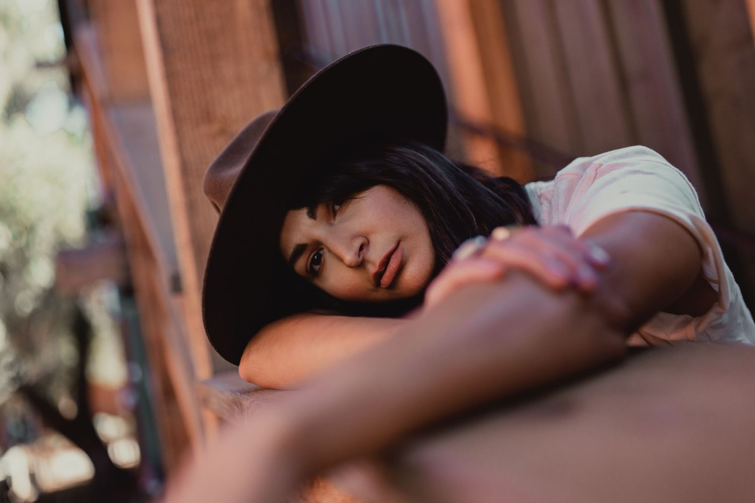 Portrait of someone wearing a black hat while lying down in warm lighting.