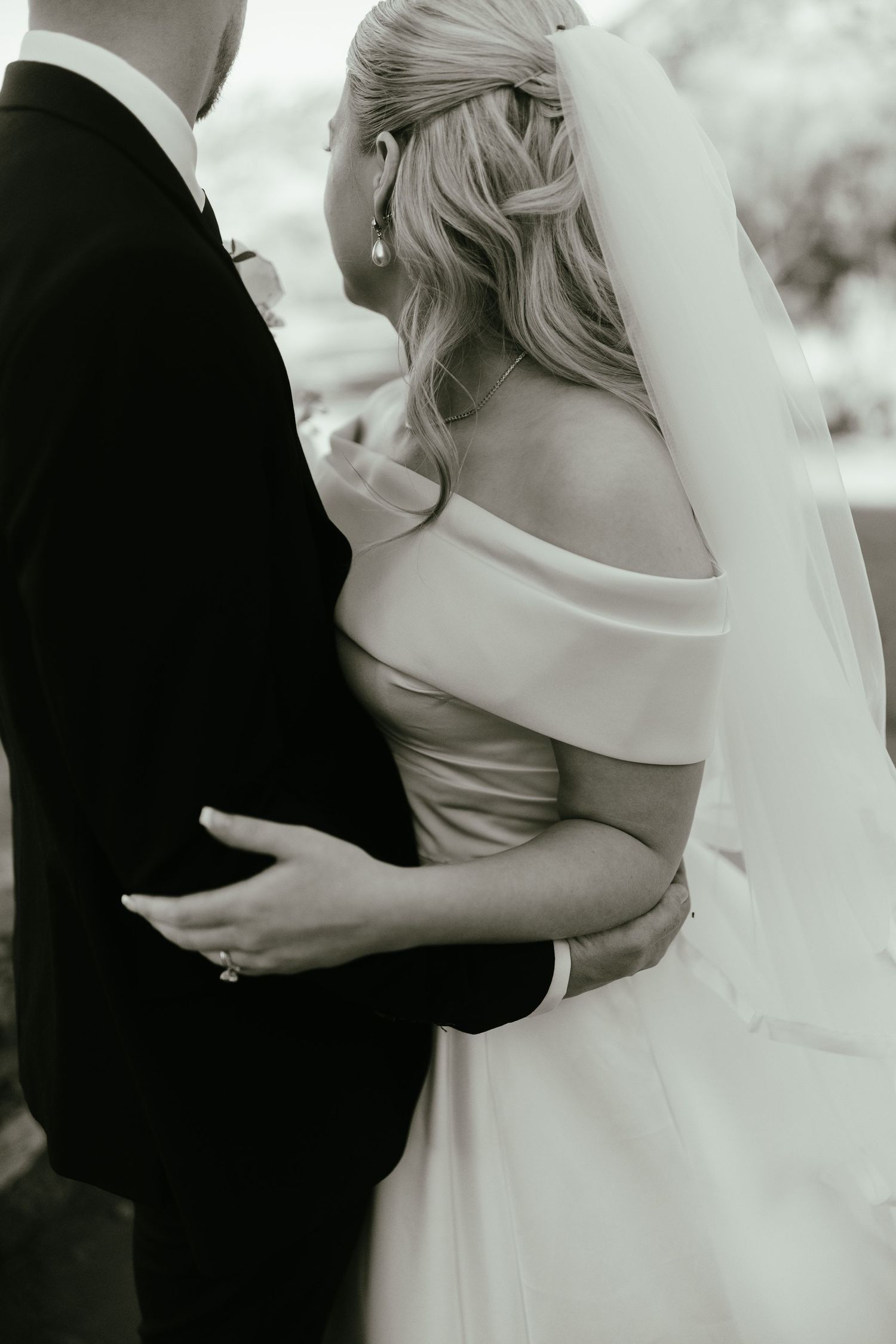 Tender embrace between newlyweds in elegant wedding attire.