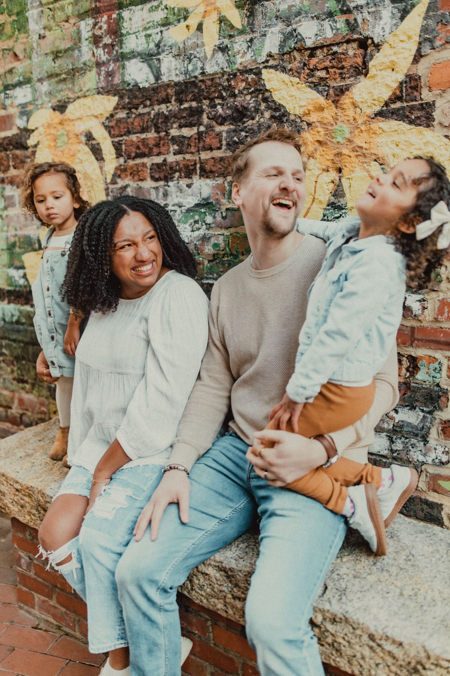Family portrait series against weathered brick wall showing playful interactions.