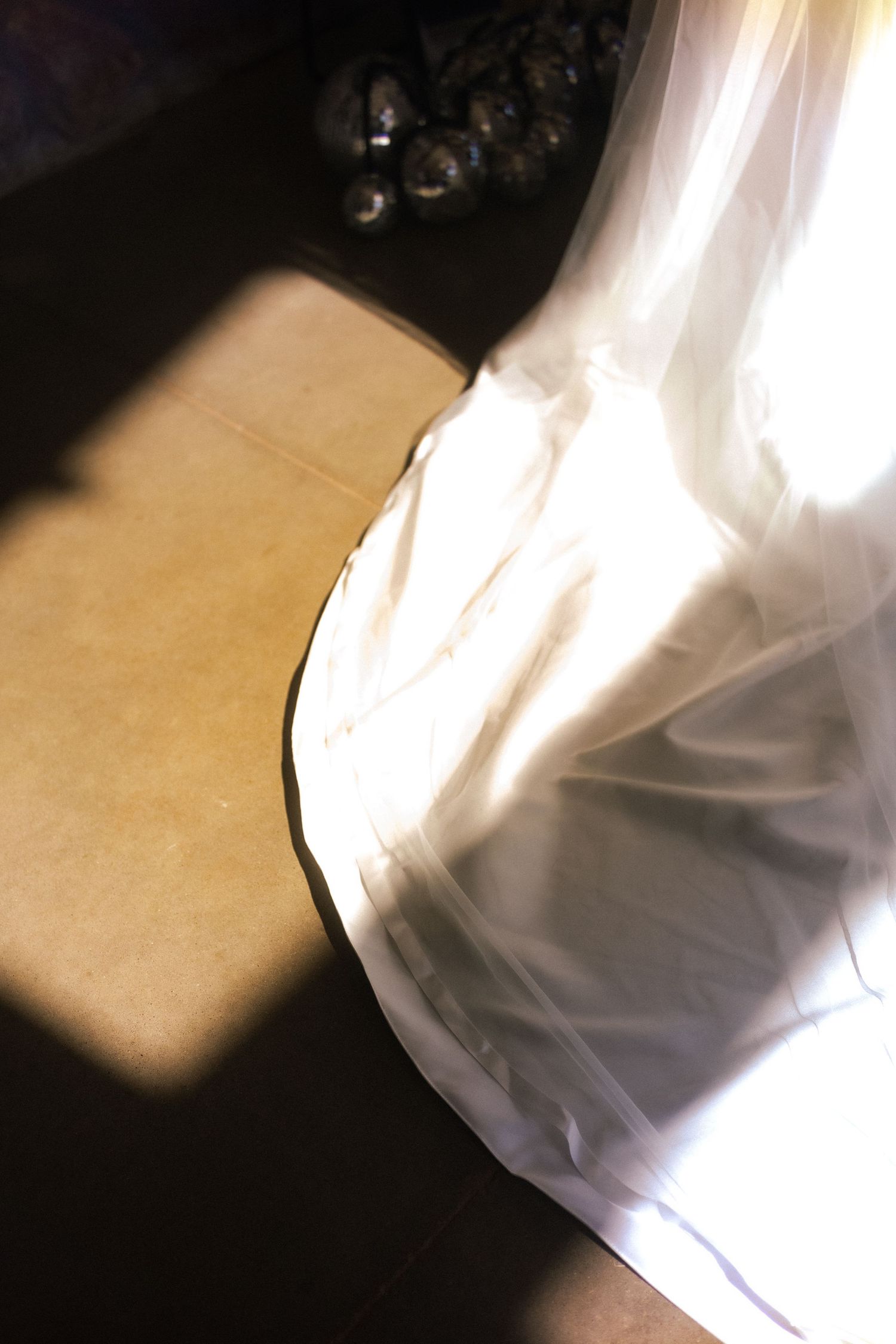 Artistic detail shot of flowing white wedding dress fabric with dramatic shadows.