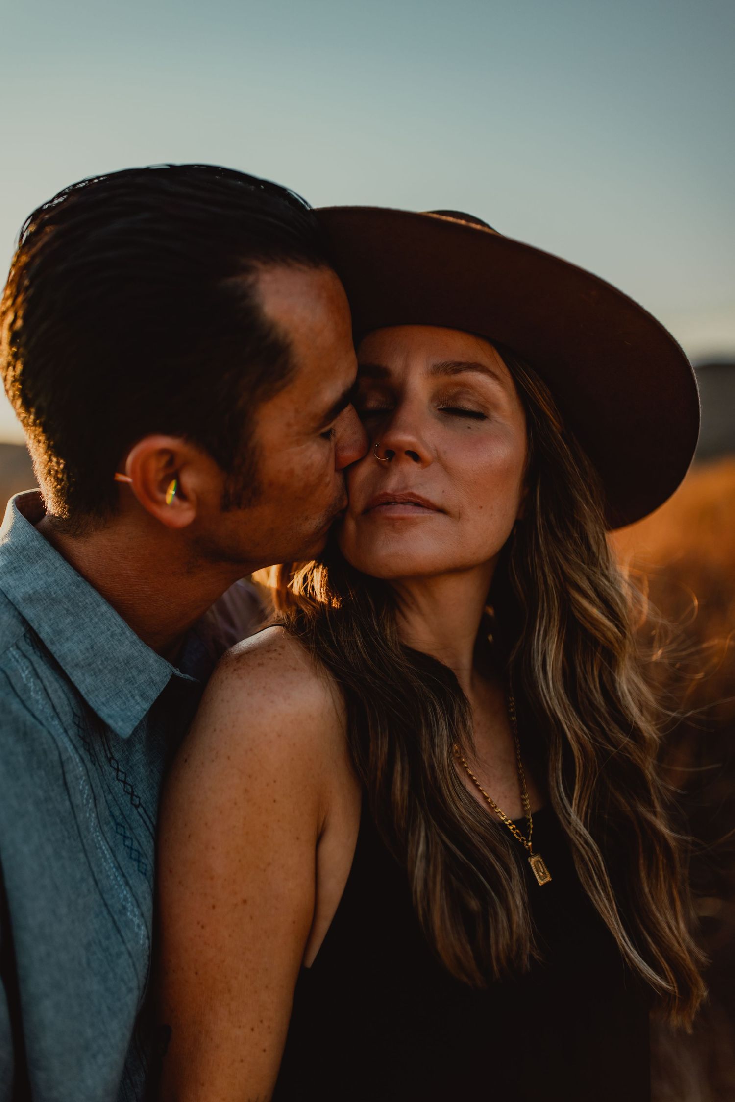 Romantic couple embracing during golden hour sunset photoshoot.