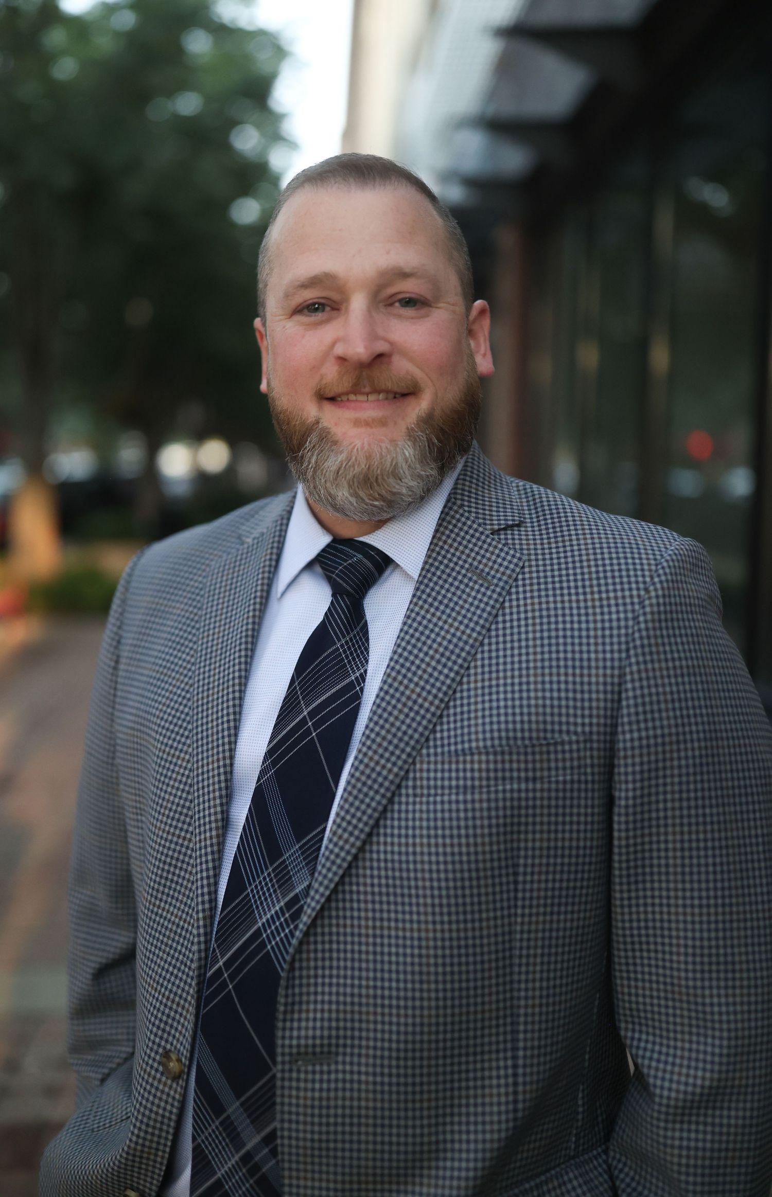 Professional headshots showing a bearded man in gray suit jacket and striped tie.