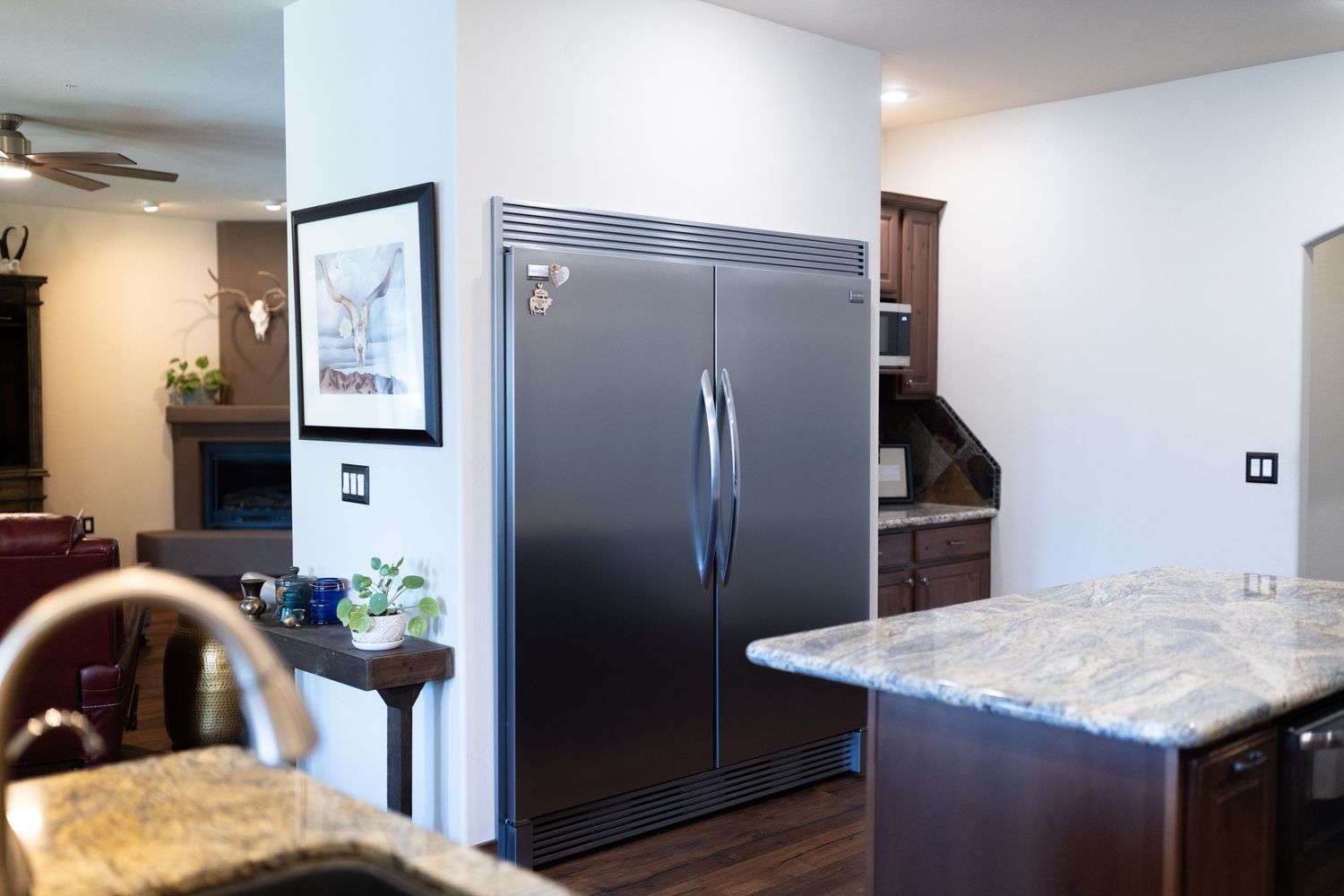 Modern luxury apartment interior showcasing dark wood cabinets, stainless appliances and granite countertops in an open layout.