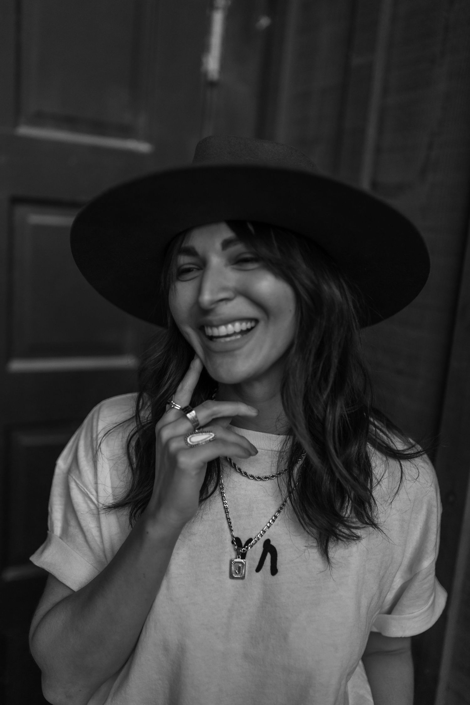 Black and white portrait of someone in a hat and t-shirt laughing joyfully.