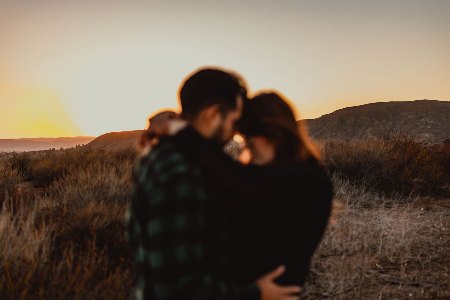 Romantic sunset silhouettes in a mountainous landscape during golden hour.