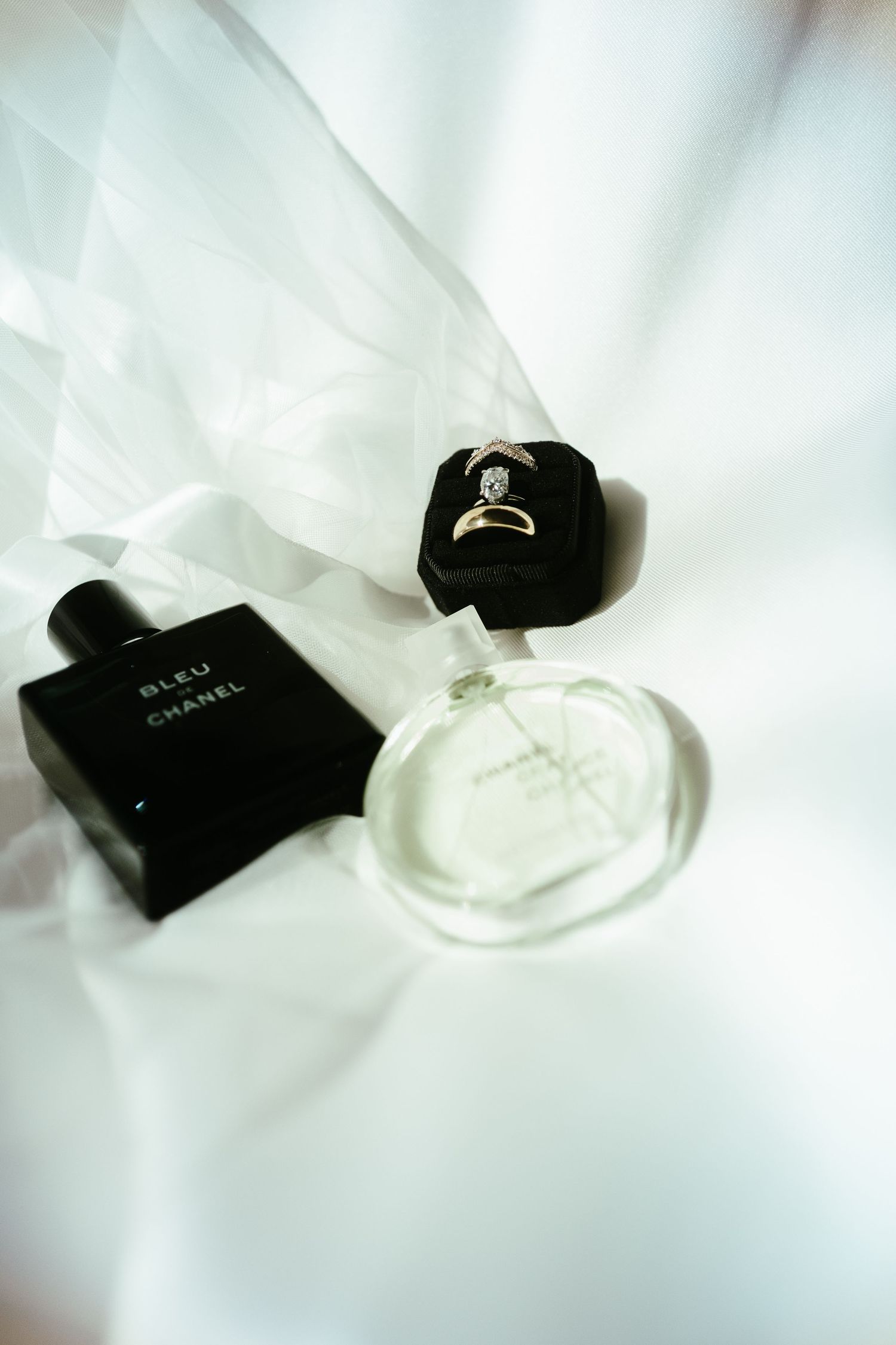Wedding rings and jewelry displayed on white fabric with soft lighting.