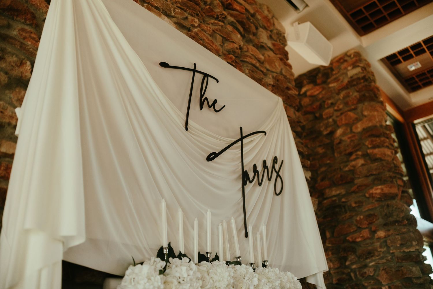 White wedding dress details hanging against rustic stone wall in preparation for ceremony.