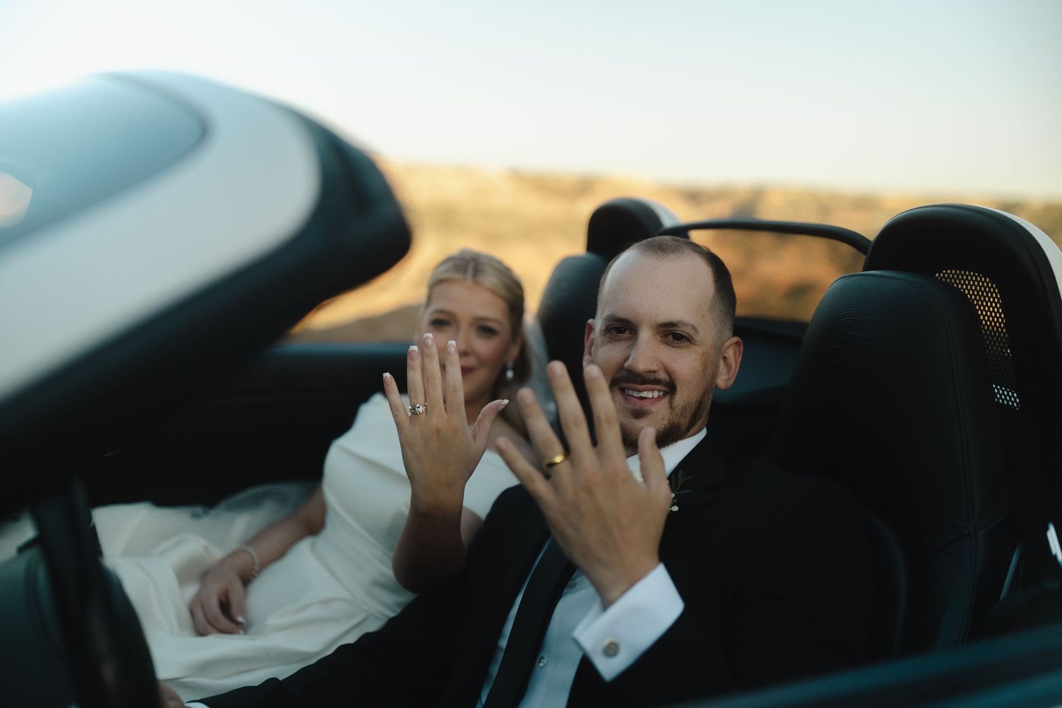 Candid wedding moments captured through car windows during golden hour.