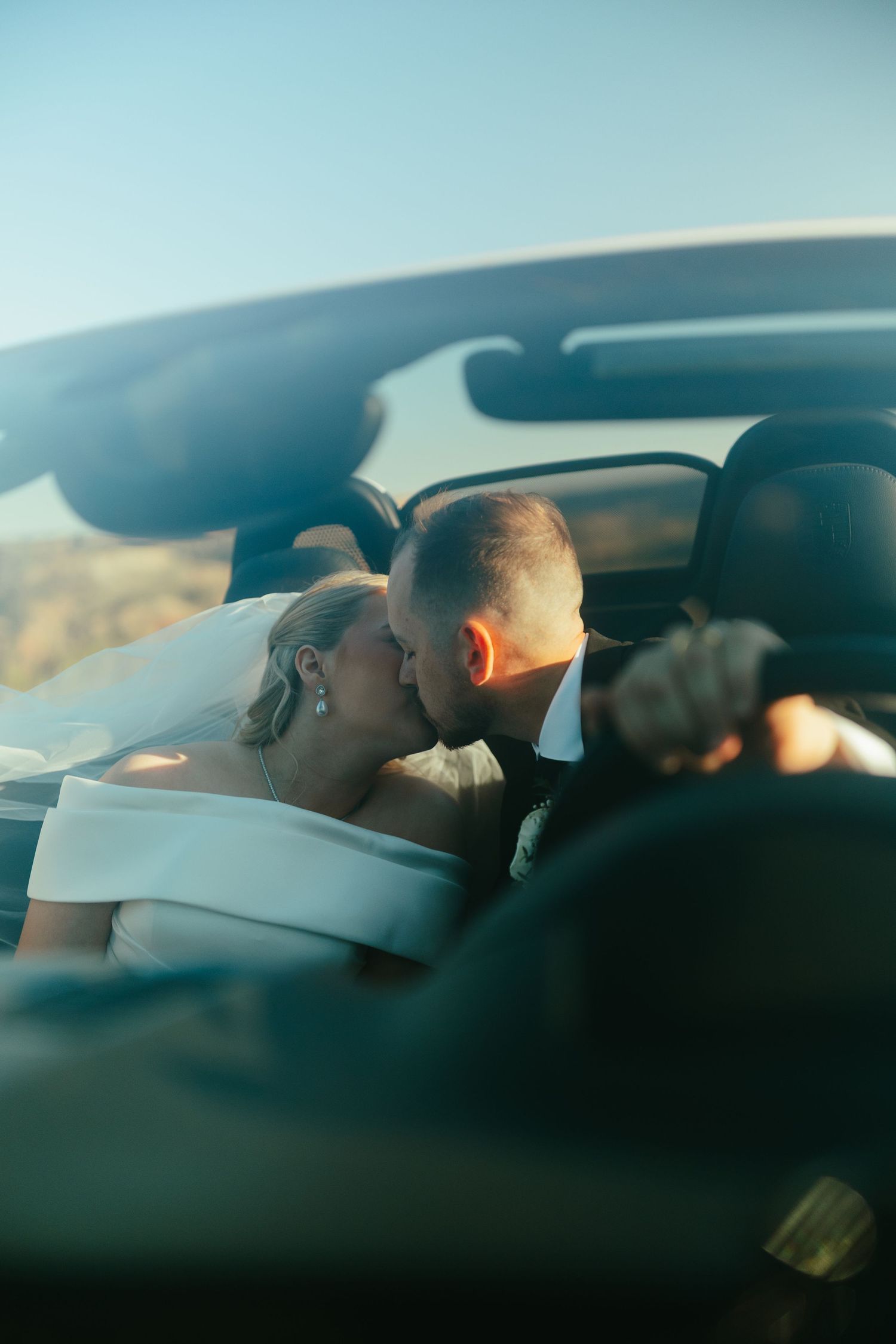 Romantic car moment captured through windshield with soft natural lighting.