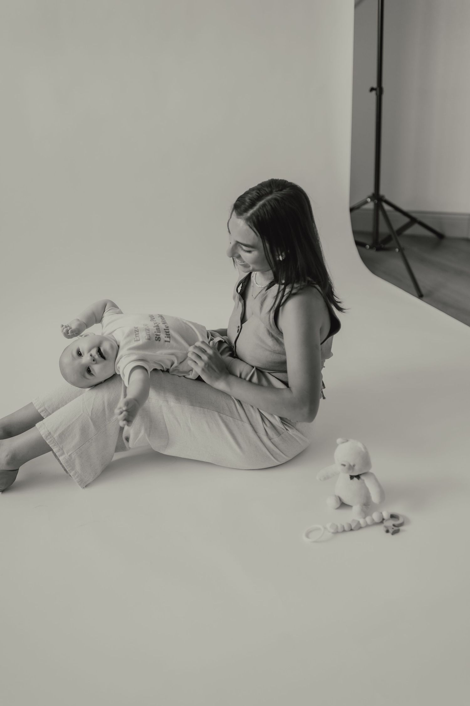 A series of black and white studio portraits showing intimate mother and baby moments on white background.