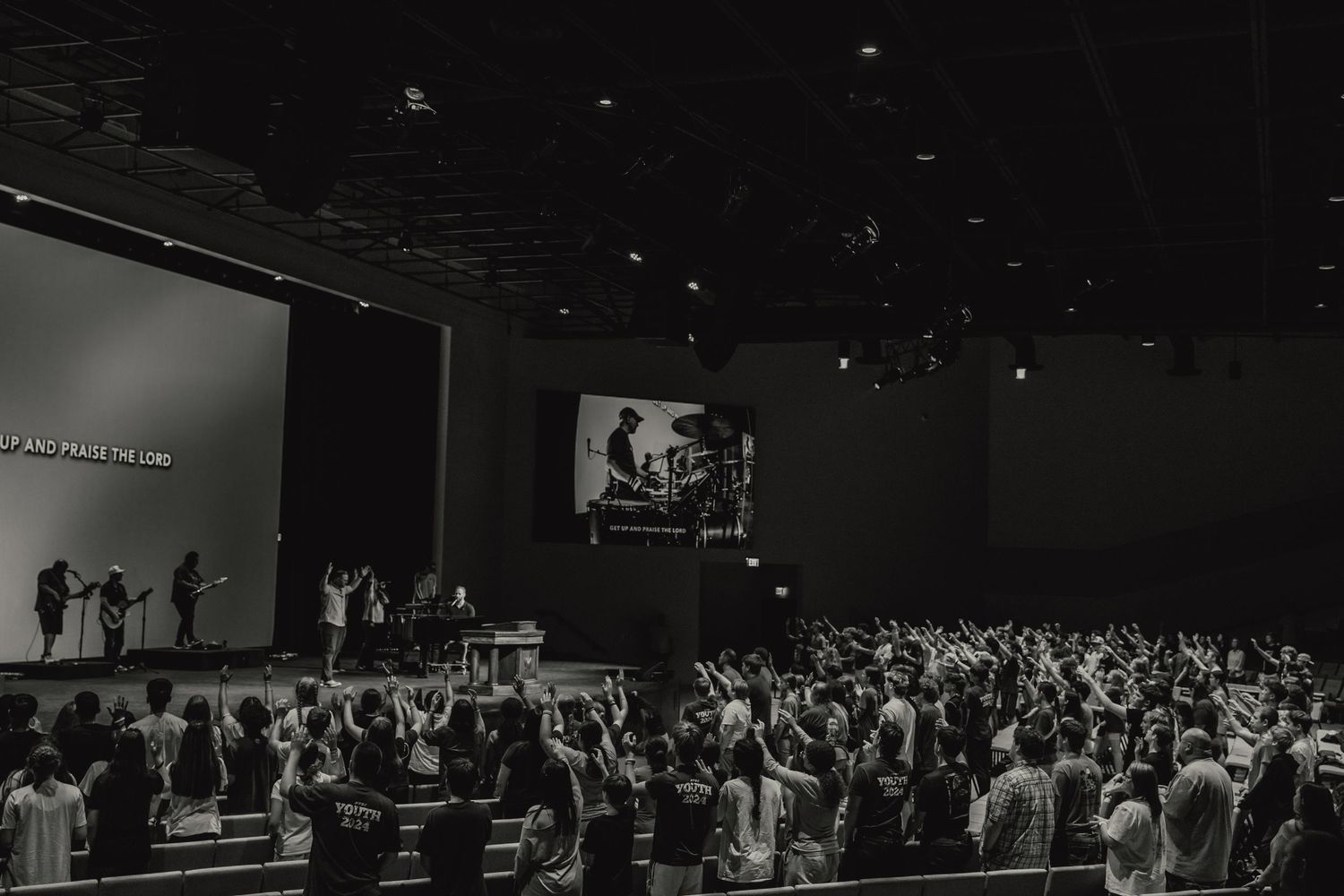 Wide shot of a large crowd gathered in a dark auditorium for an event.