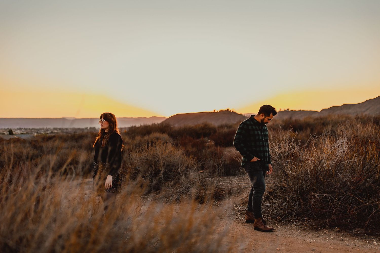Couple embracing in golden light against a mountain landscape at sunset.