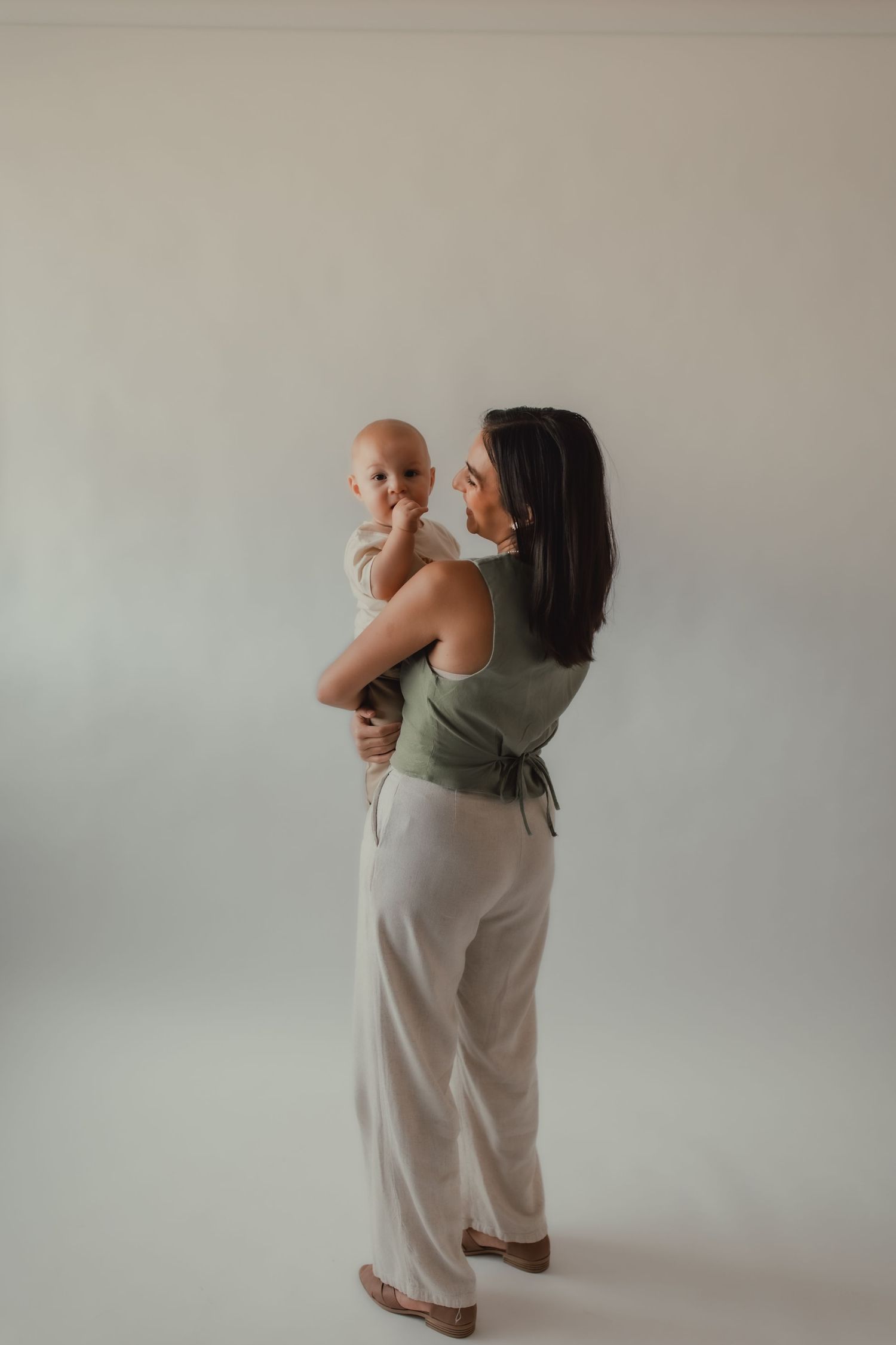 Tender moments between parent and baby in minimalist white studio setting.