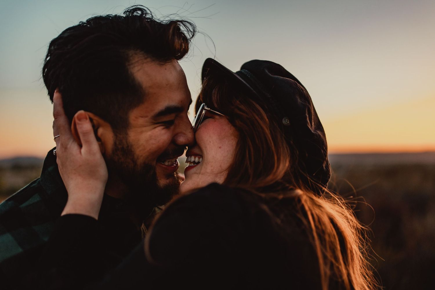 A romantic couple sharing an intimate moment during sunset in a natural outdoor setting.