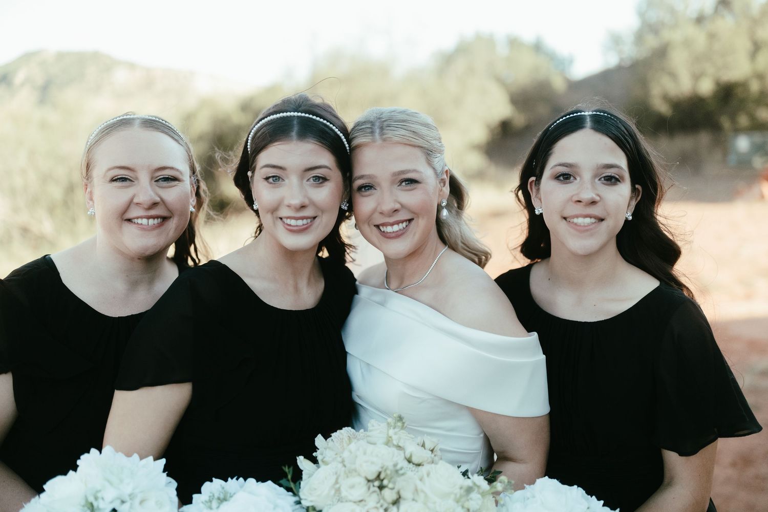 Wedding party in black and white attire posing together outdoors.