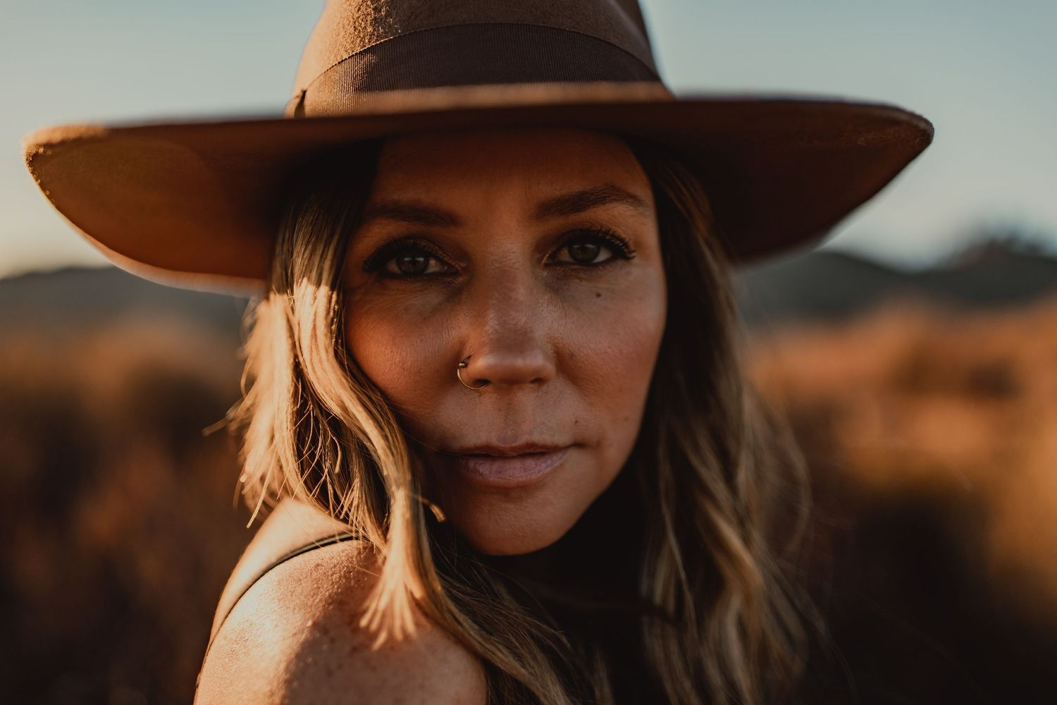 Portrait series at golden hour in a desert landscape with warm sunset lighting and mountains in background.