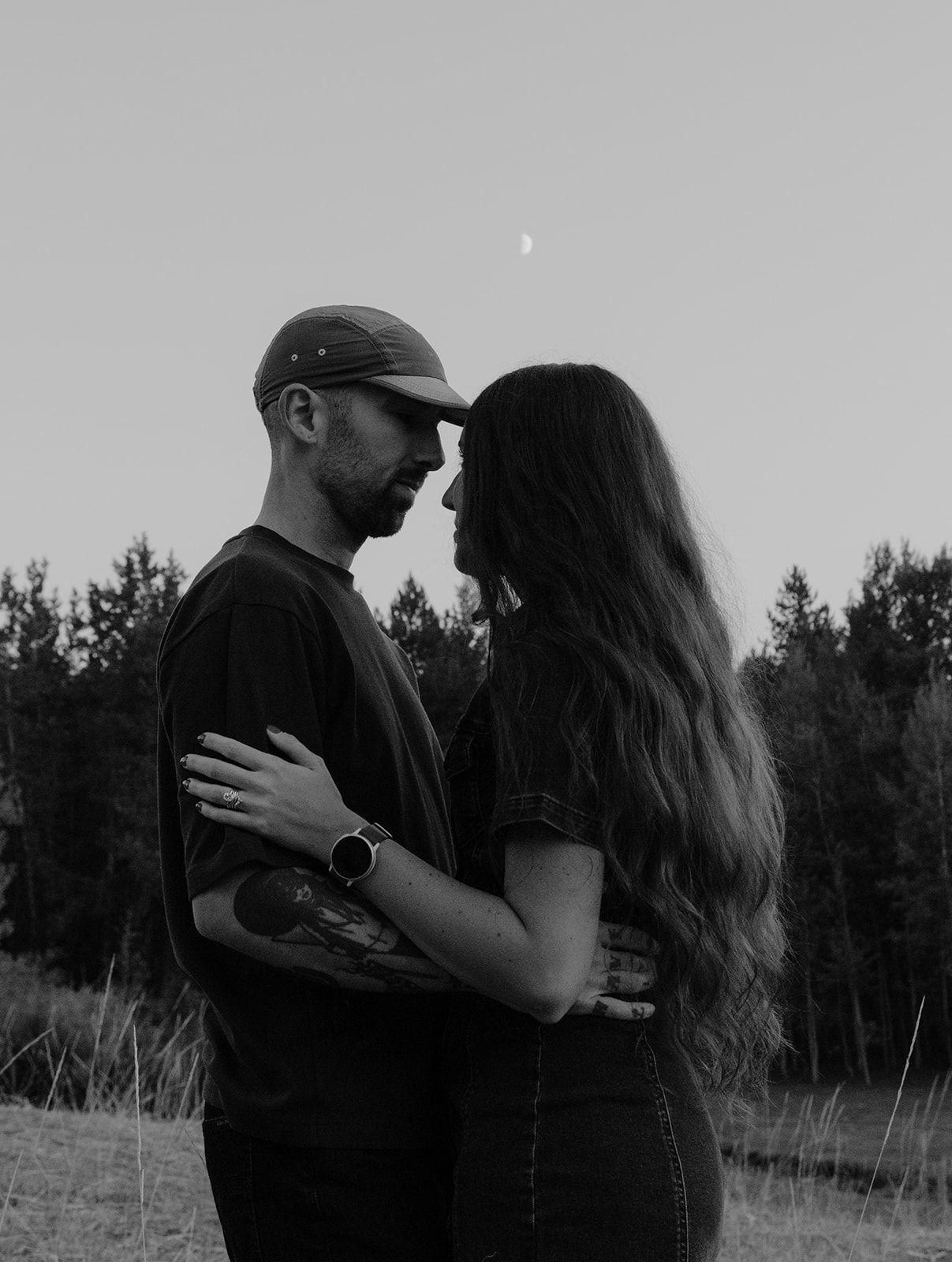 Couples photoshoot in Idaho Falls, Idaho at dusk with the moon in the background, intimate engagement photos