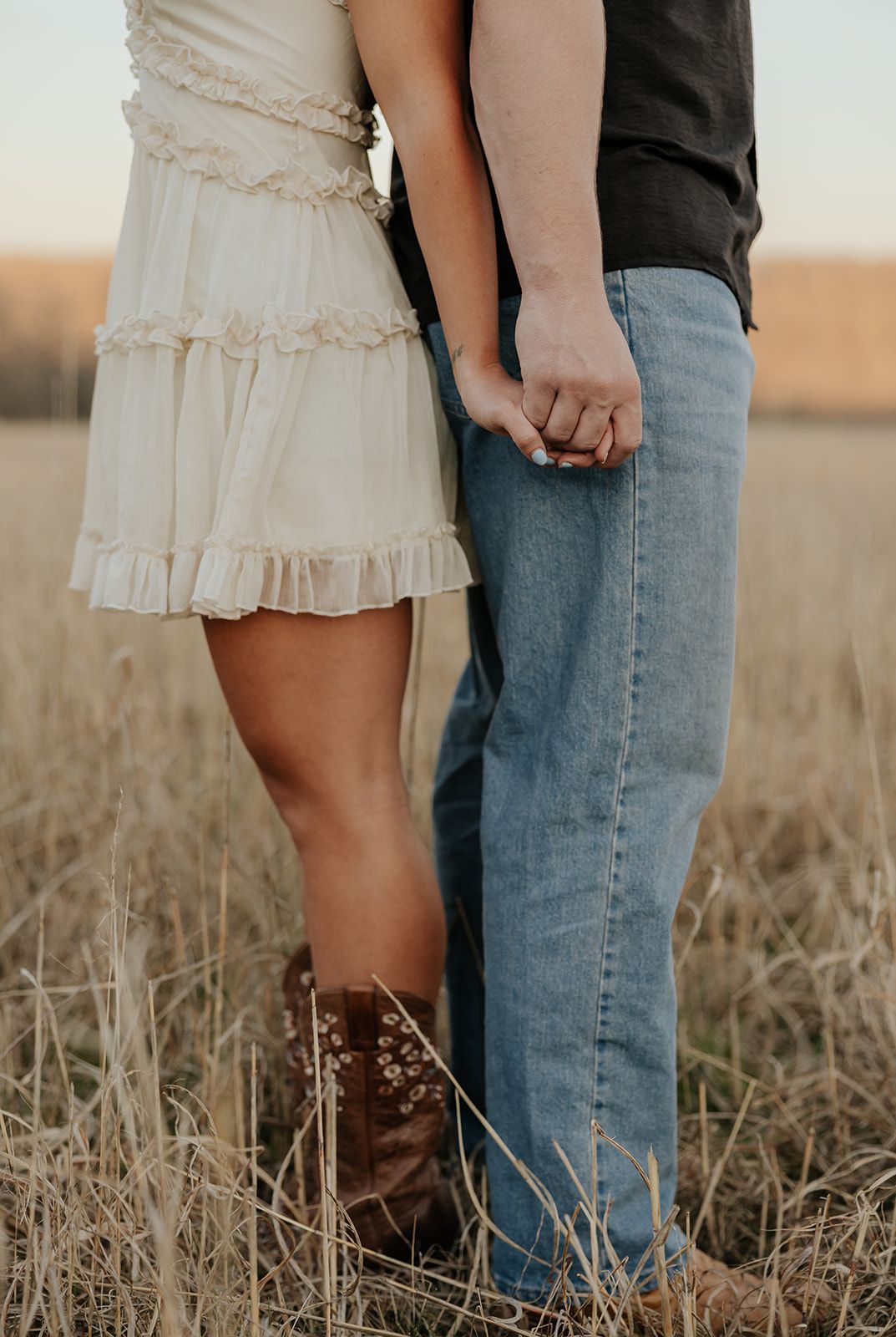 Couple holding hands standing back to back in a field