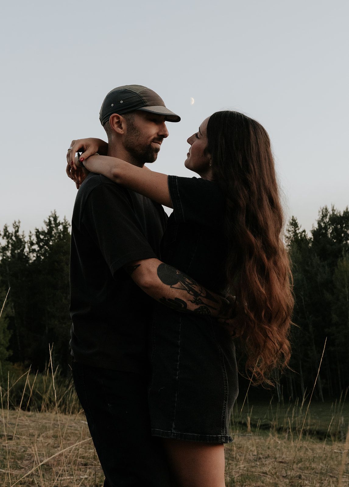Couples photoshoot in Idaho Falls, Idaho at dusk with the moon in the background, intimate engagement photos