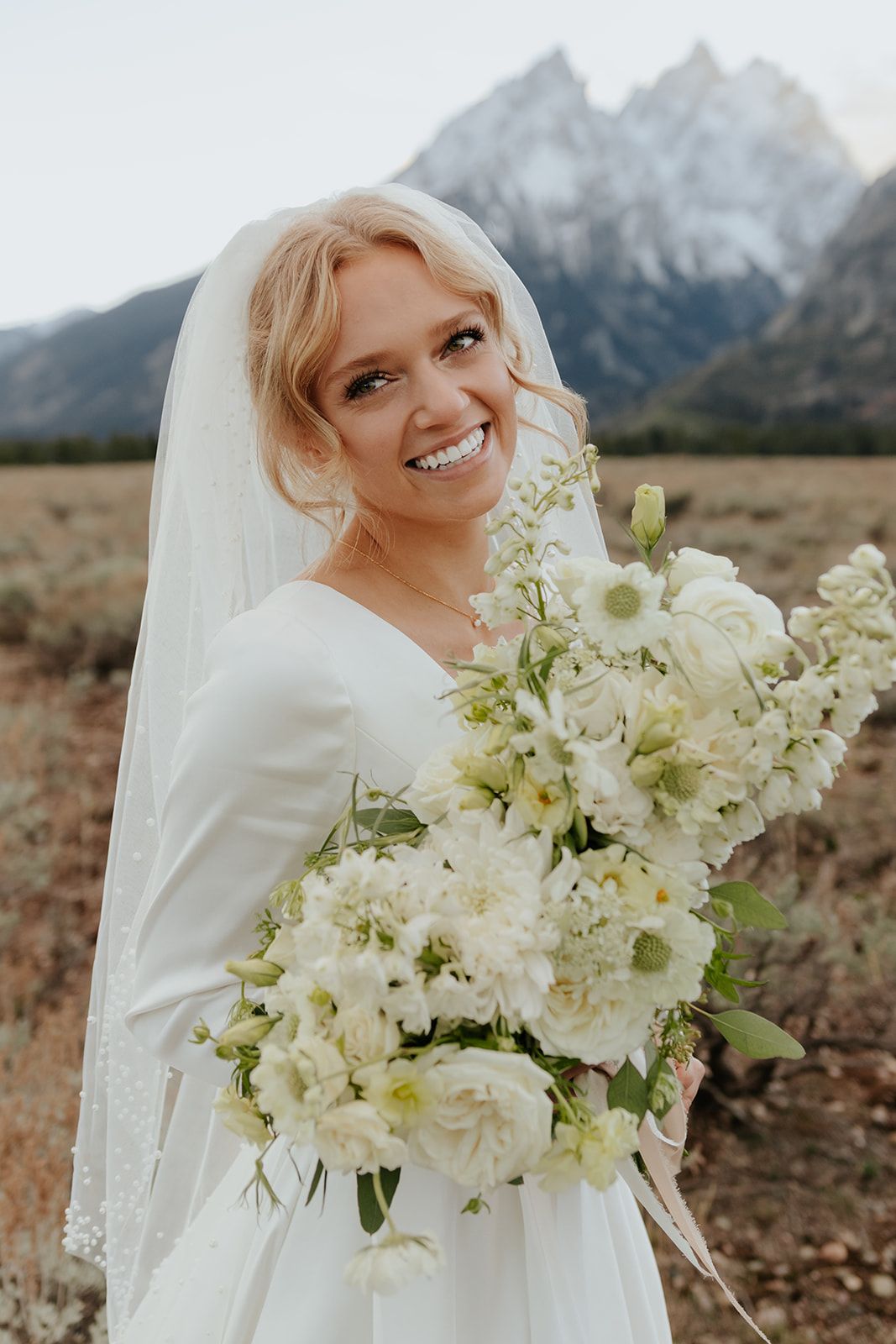 Bridal photos in Grand Teton National Park at sunset during the fall. Cream and white wedding bouquet. Bridal veil with pearls. Bridal updo.