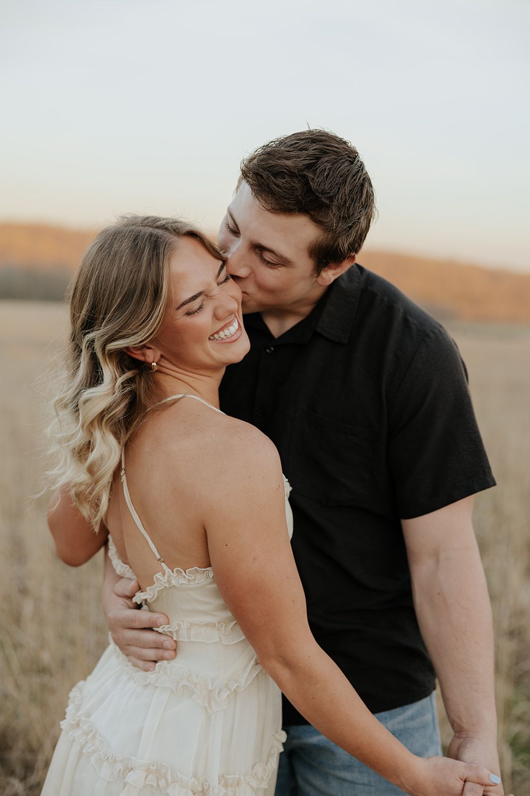 Engagement photos in a field at sunset