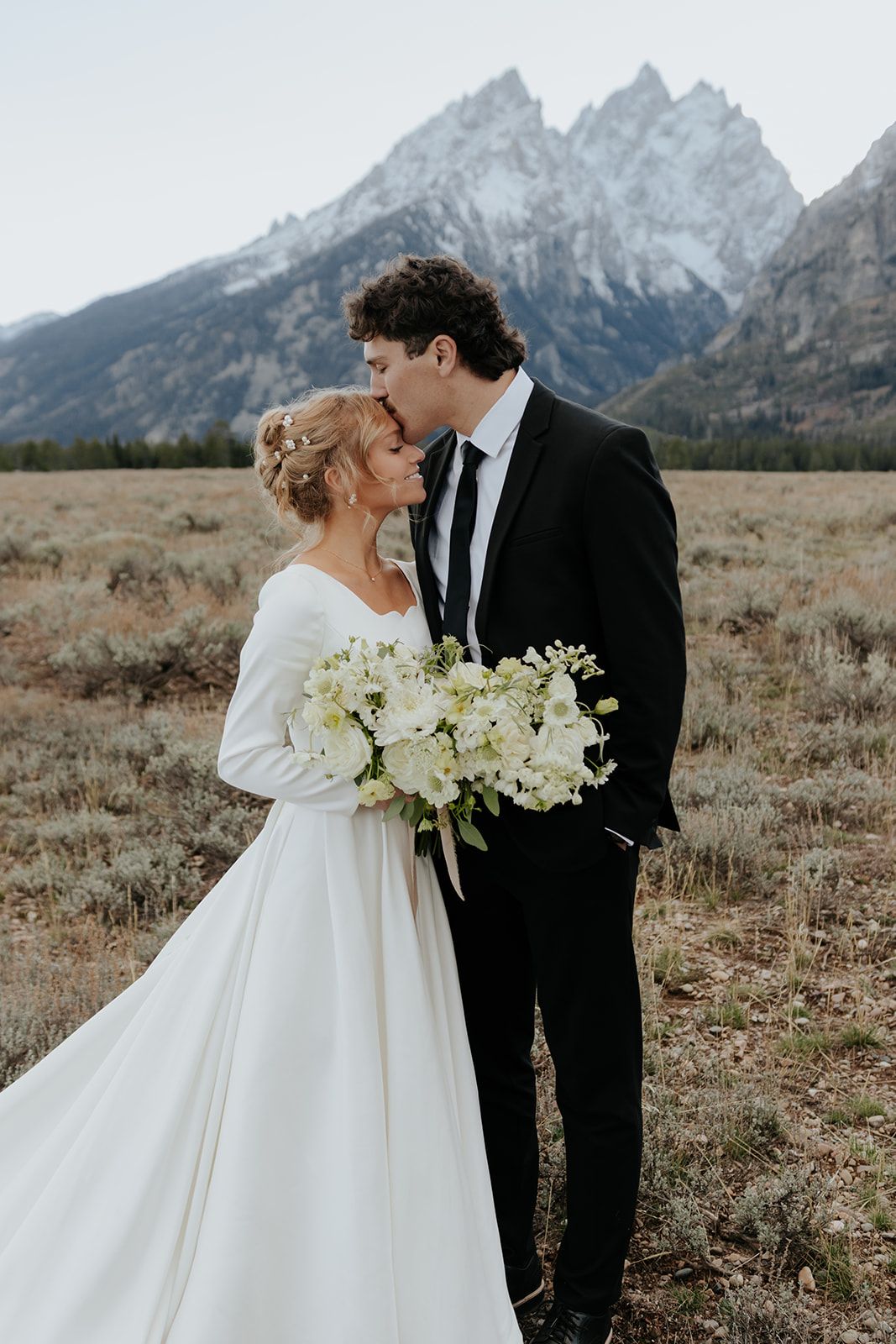 Groom kissing bride's forehead during bridal photos in Grand Teton National Park