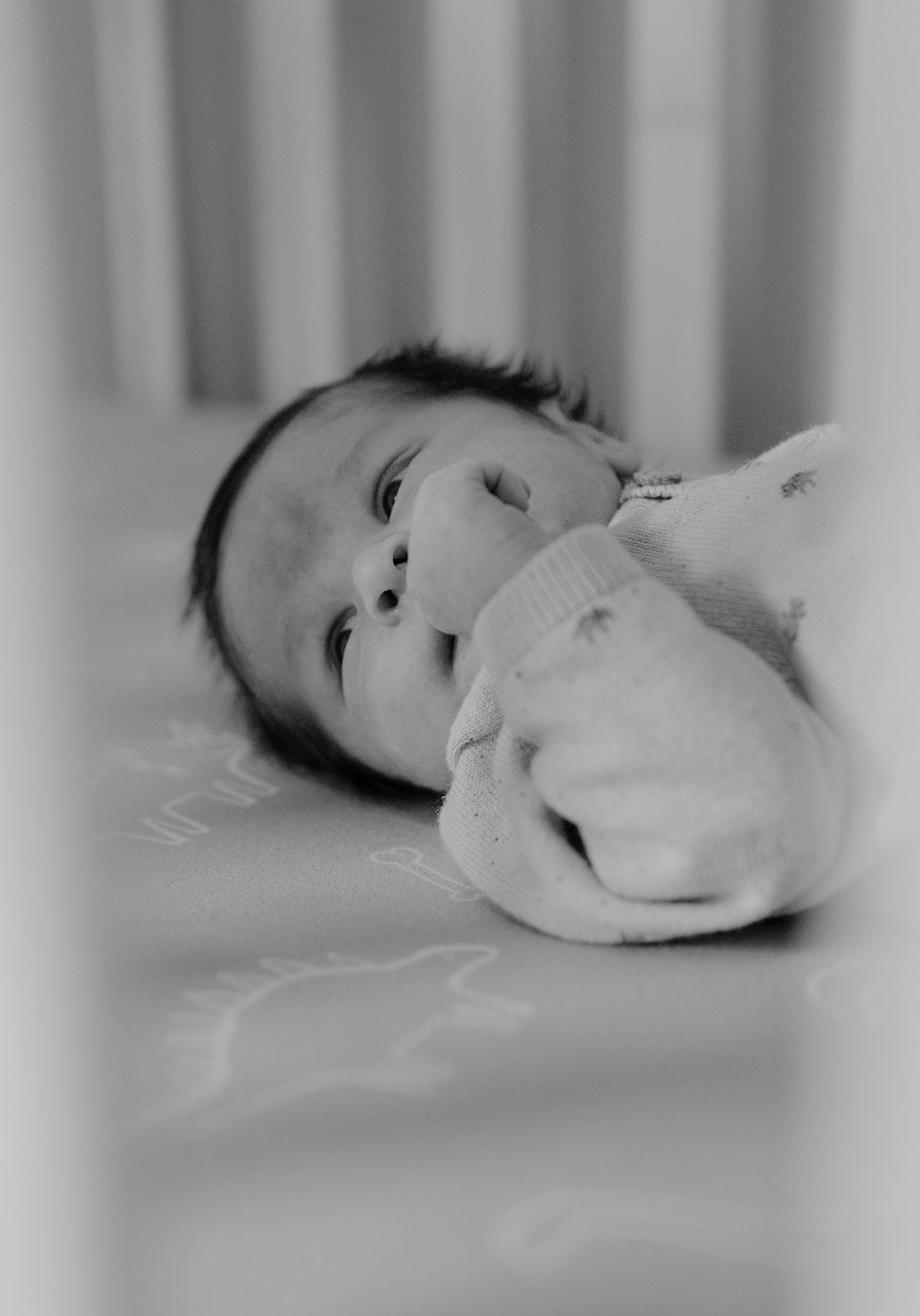 Newborn in crib, candid moments during newborn photoshoot in Springfield, Missouri. Black and White photo