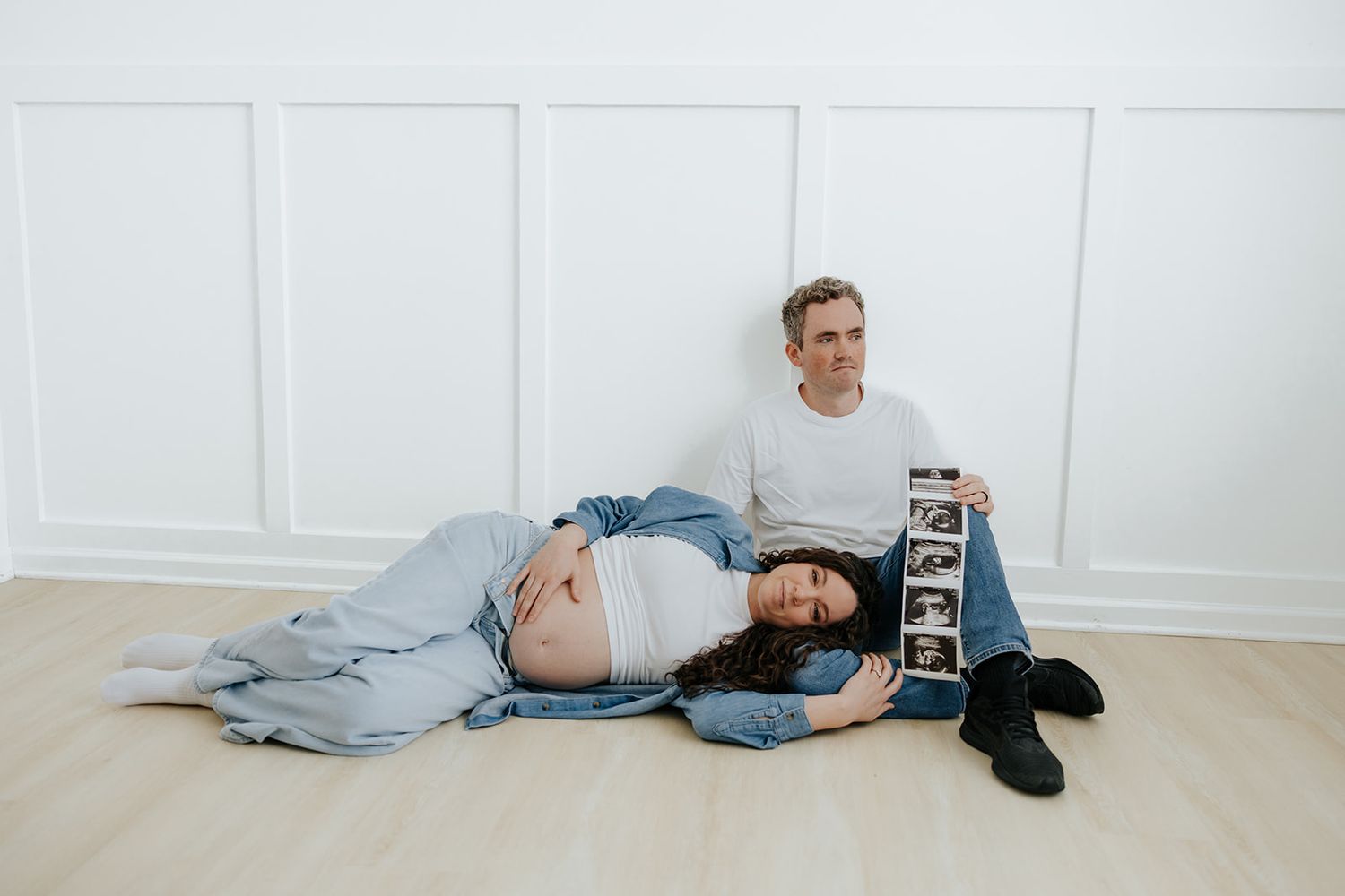 Studio maternity photoshoot holding ultrasound pictures