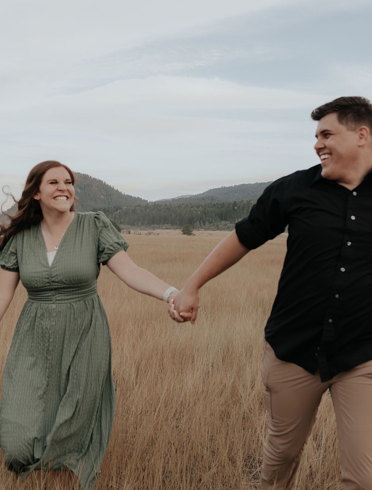 Couple running in field near Palisades Reservoir, couples engagement photoshoot