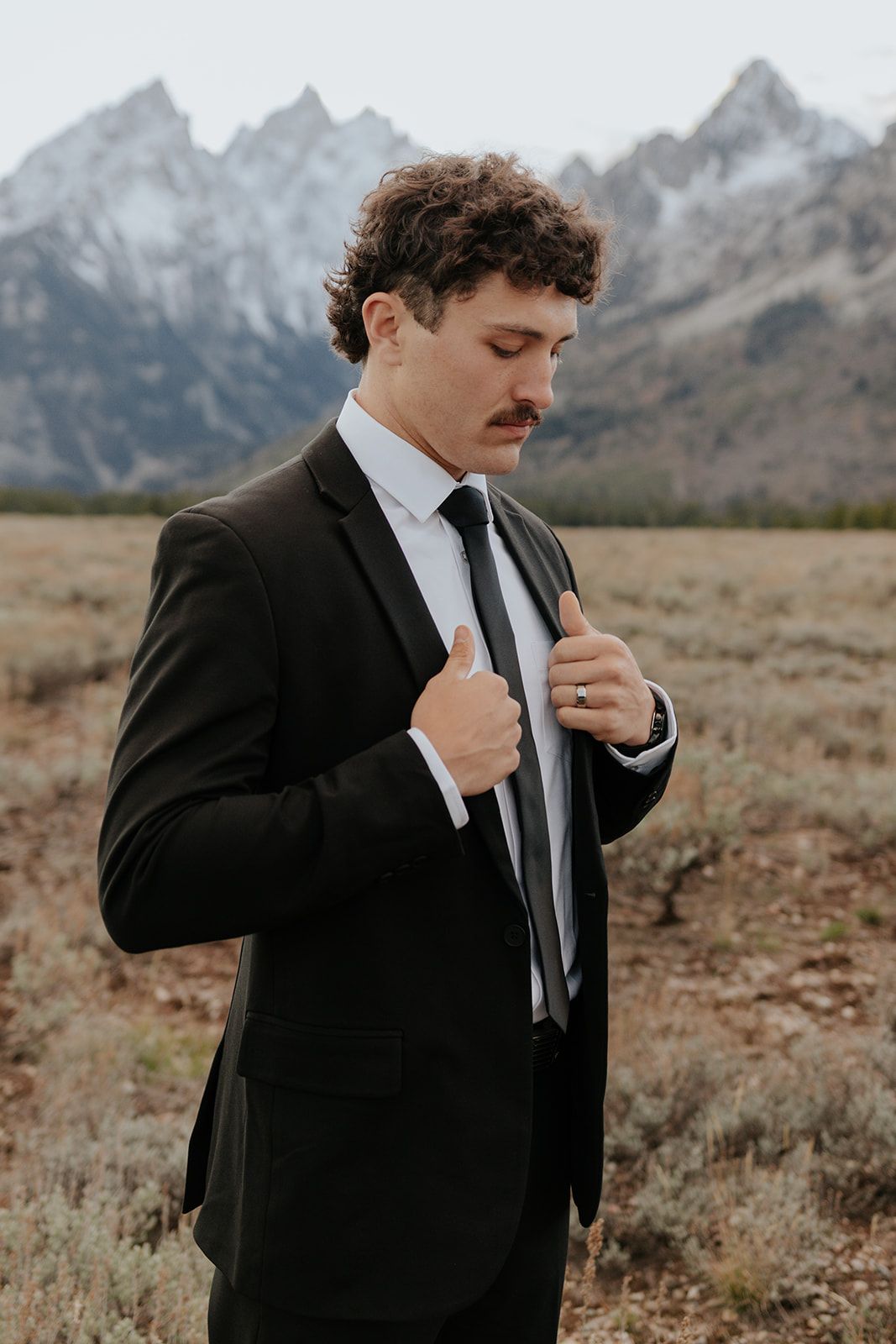 Groom fixing suit and tie for photoshoot in Grand Teton National Park