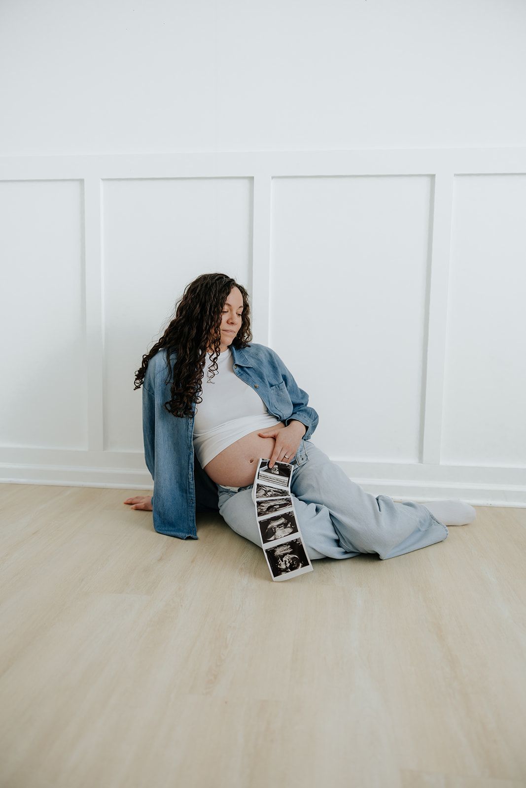 Maternity photoshoot in a studio, holding ultrasound photos
