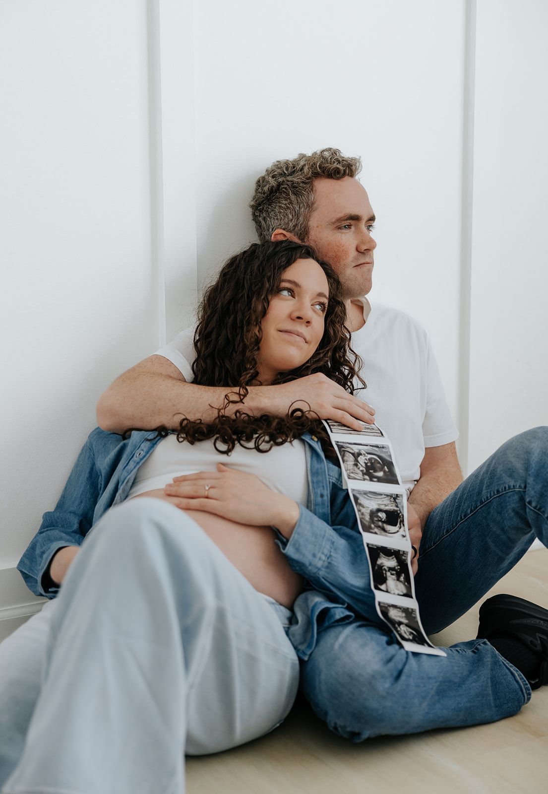 Studio maternity photoshoot holding ultrasound pictures