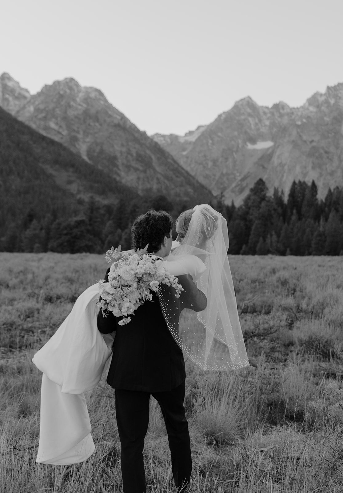 Bridal photoshoot in Grand Teton National Park at sunset in October. Groom carrying Bride. Mount Moran. Black and White bridal photo