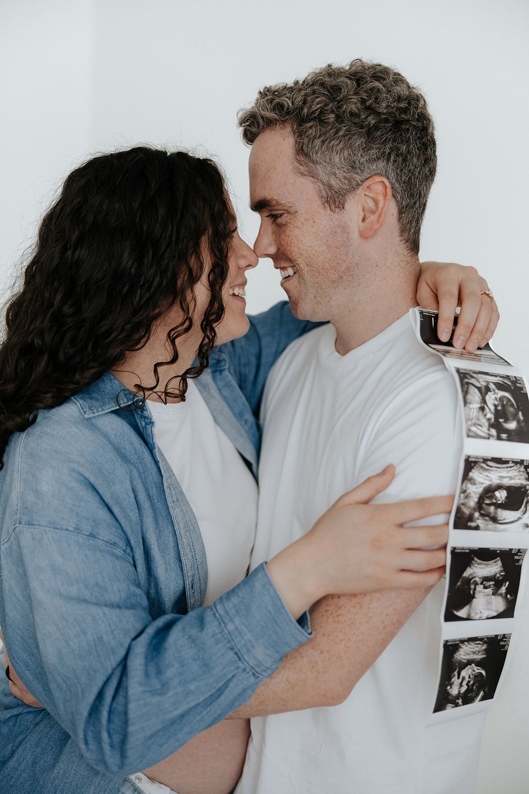 Studio maternity photoshoot holding ultrasound pictures