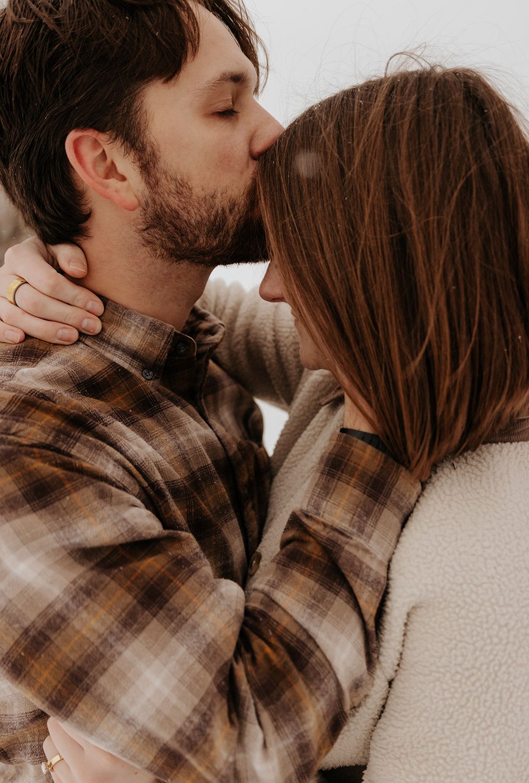 Couples engagement photos in Springfield, Missouri in the snow, kiss on the forehead
