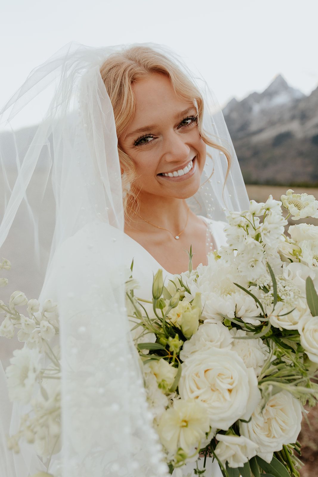 Picture of bride with veil and bouquet of cream and white flowers. Grand Teton National Park bridal photoshoot