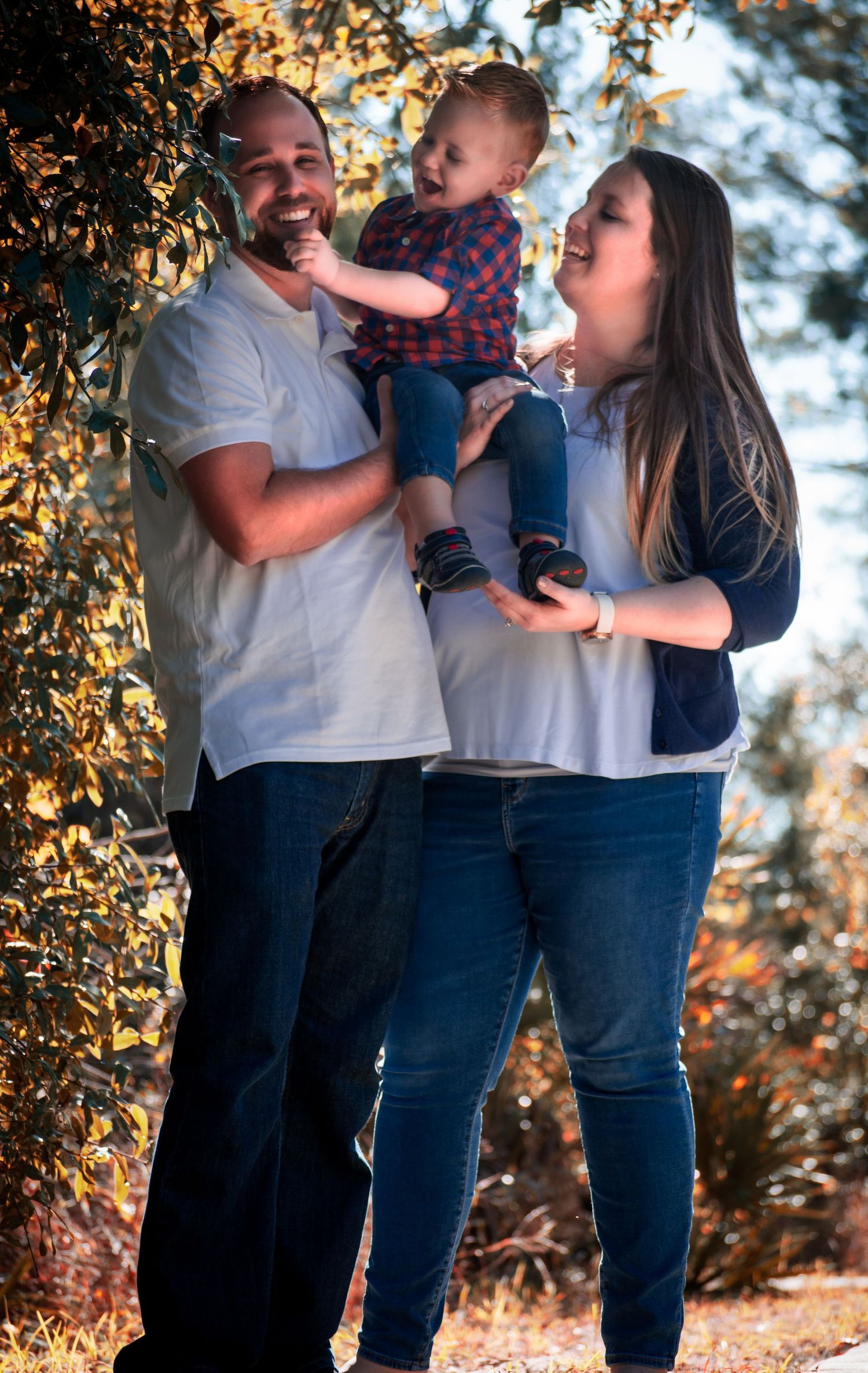 Outdoor family photoshoot with golden autumn lighting filtering through trees.