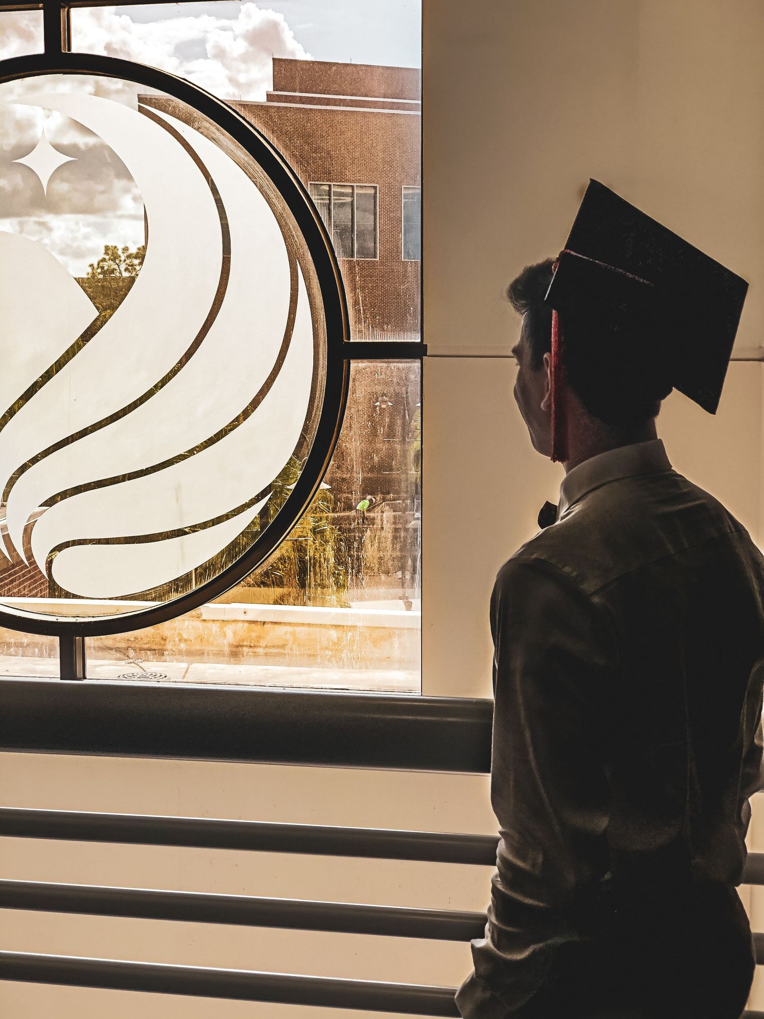 Silhouette of graduates looking through curved modern architecture window.