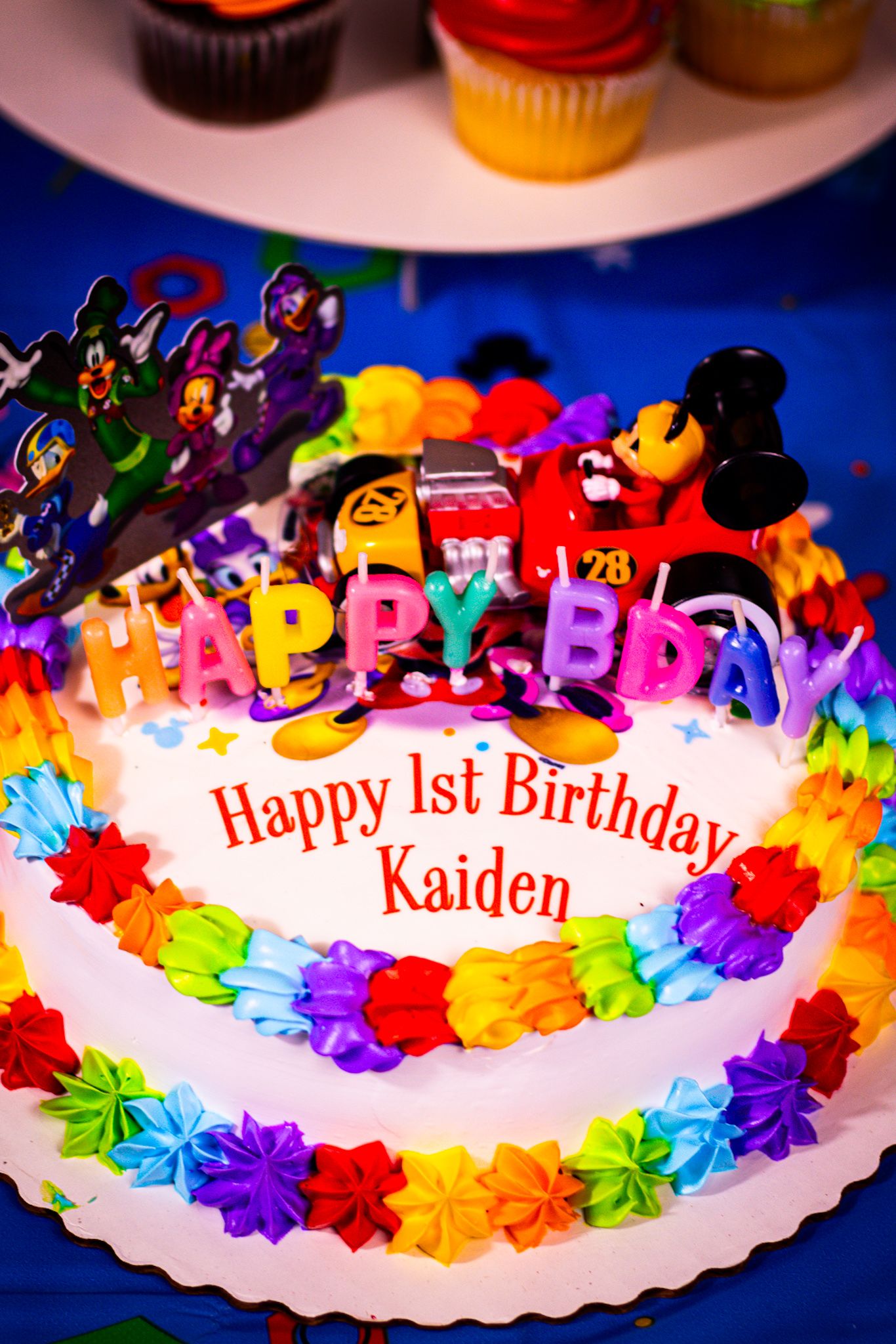 A rainbow-colored birthday cake with Disney characters and personalized birthday message.